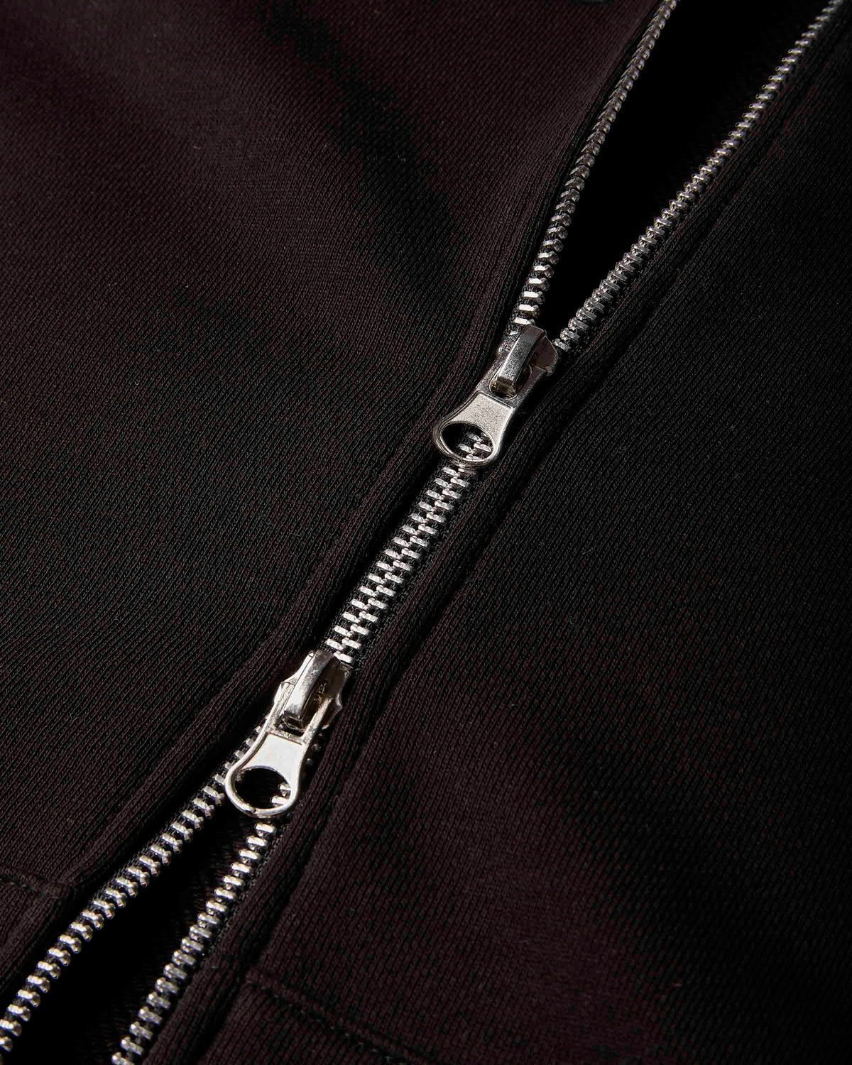 Close-up of a black fabric garment with a silver metal zipper running vertically down the center.