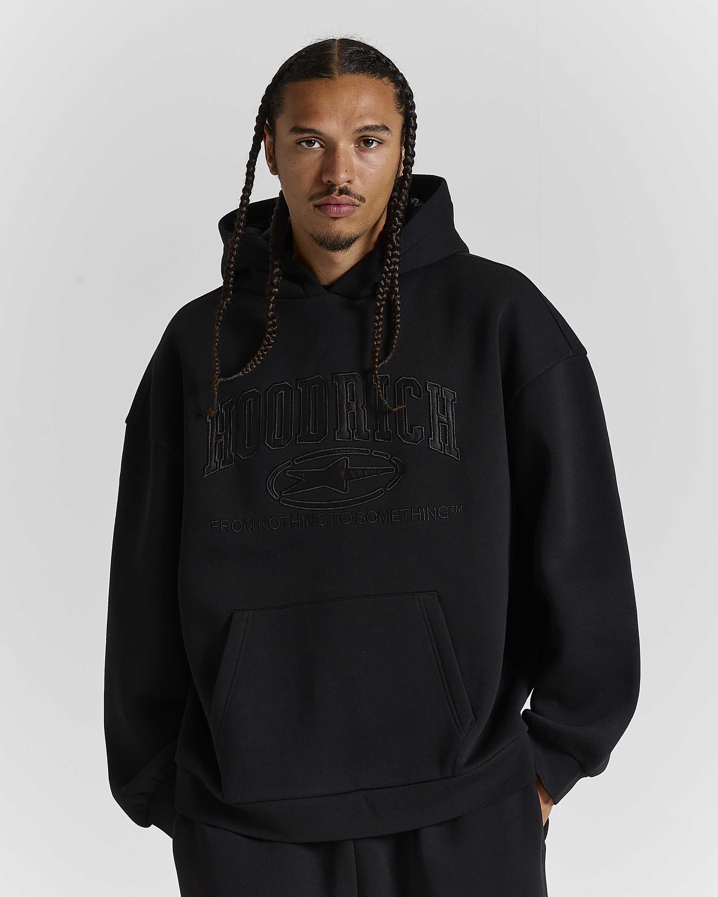 Displays a model wearing the Black 'Hoodrich' branded men's Aegis Full Tracksuit