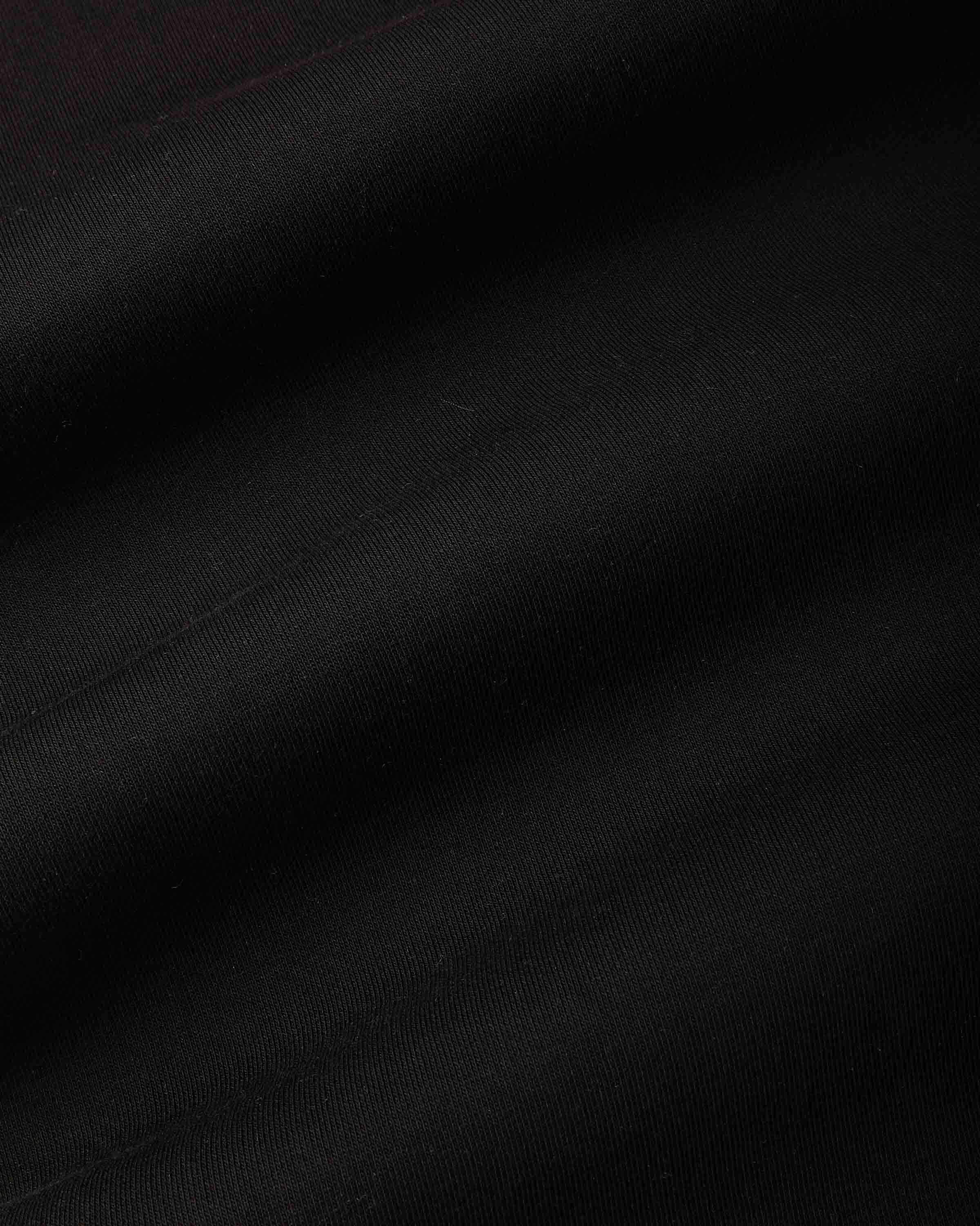 A close-up of black fabric with soft diagonal folds and a subtle woven texture.