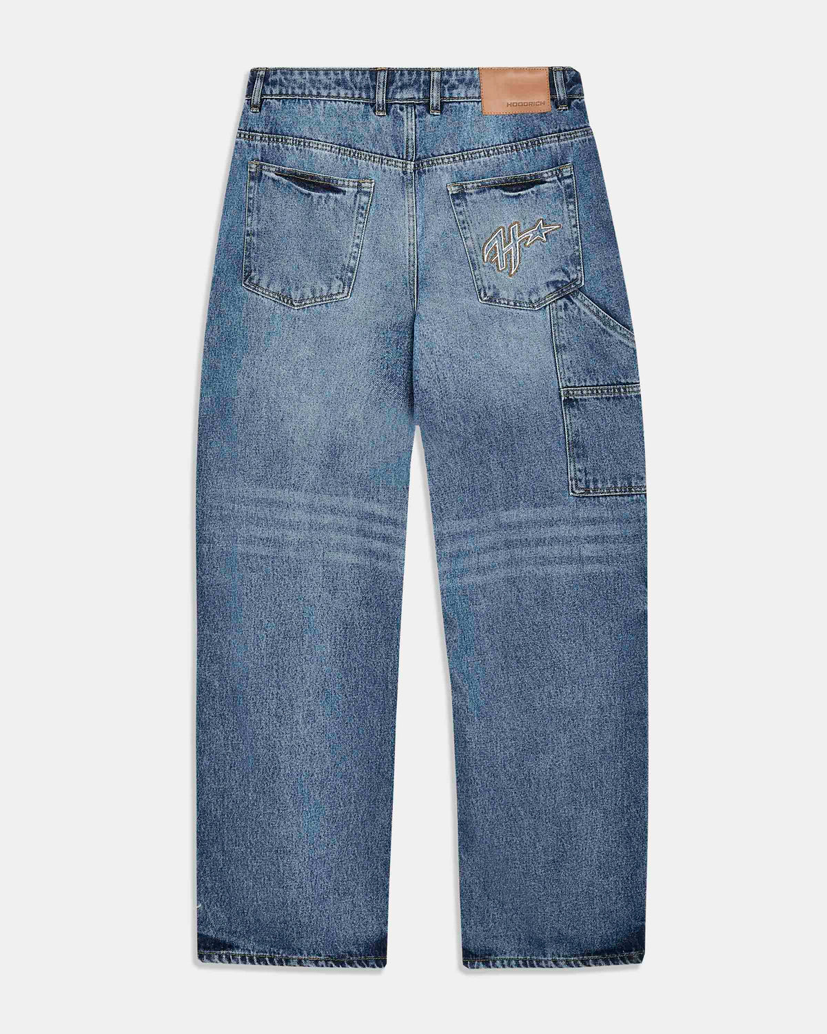 Back view of a pair of blue denim jeans with a light wash, featuring a tan leather patch on the back waistband and a stylized embroidered logo on the right back pocket.