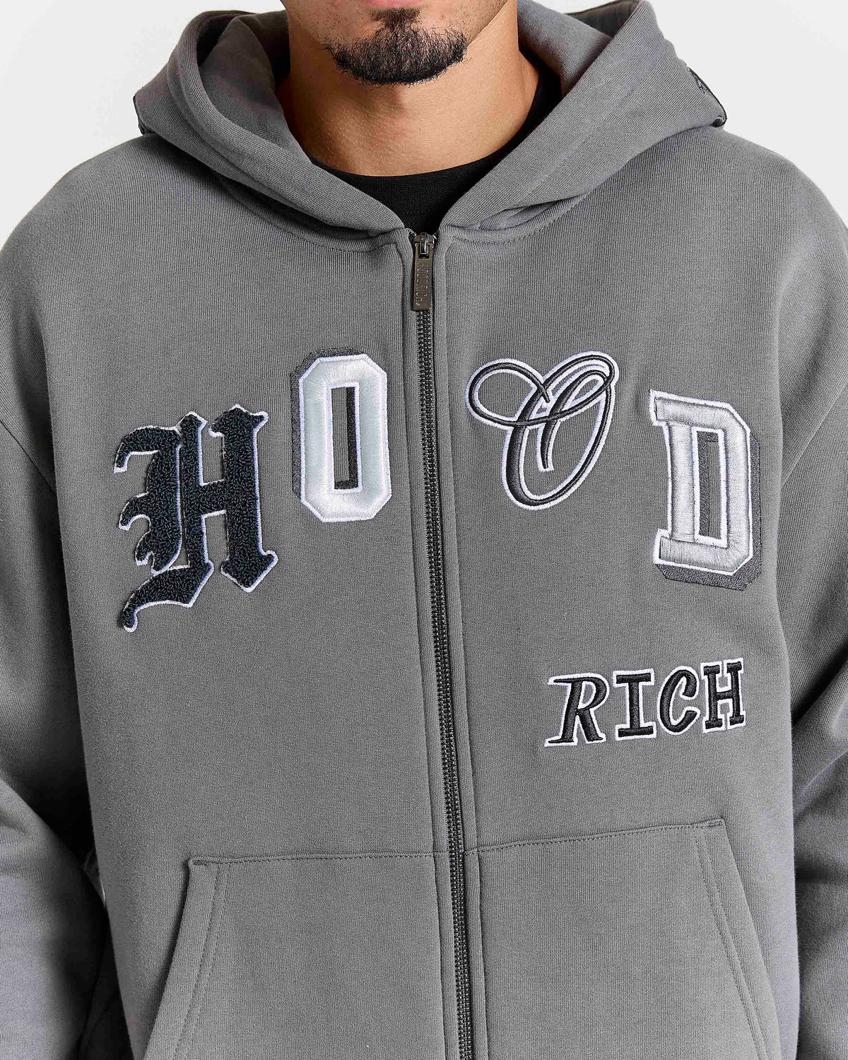 Displays a model wearing the grey lava smoke 'Hoodrich' branded Forza Oversized Zip Through Hoodie featuring the hoodrich branding details