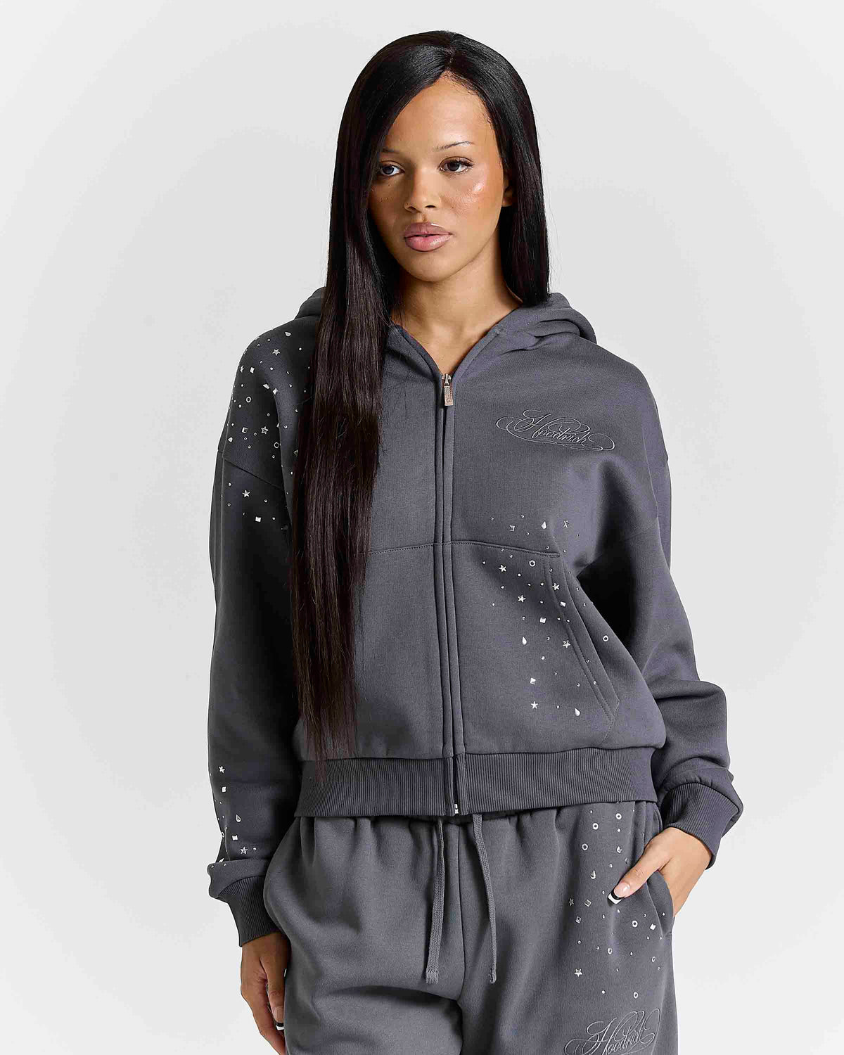 Displays a model wearing the grey 'Hoodrich' branded women's Clash Full Tracksuit