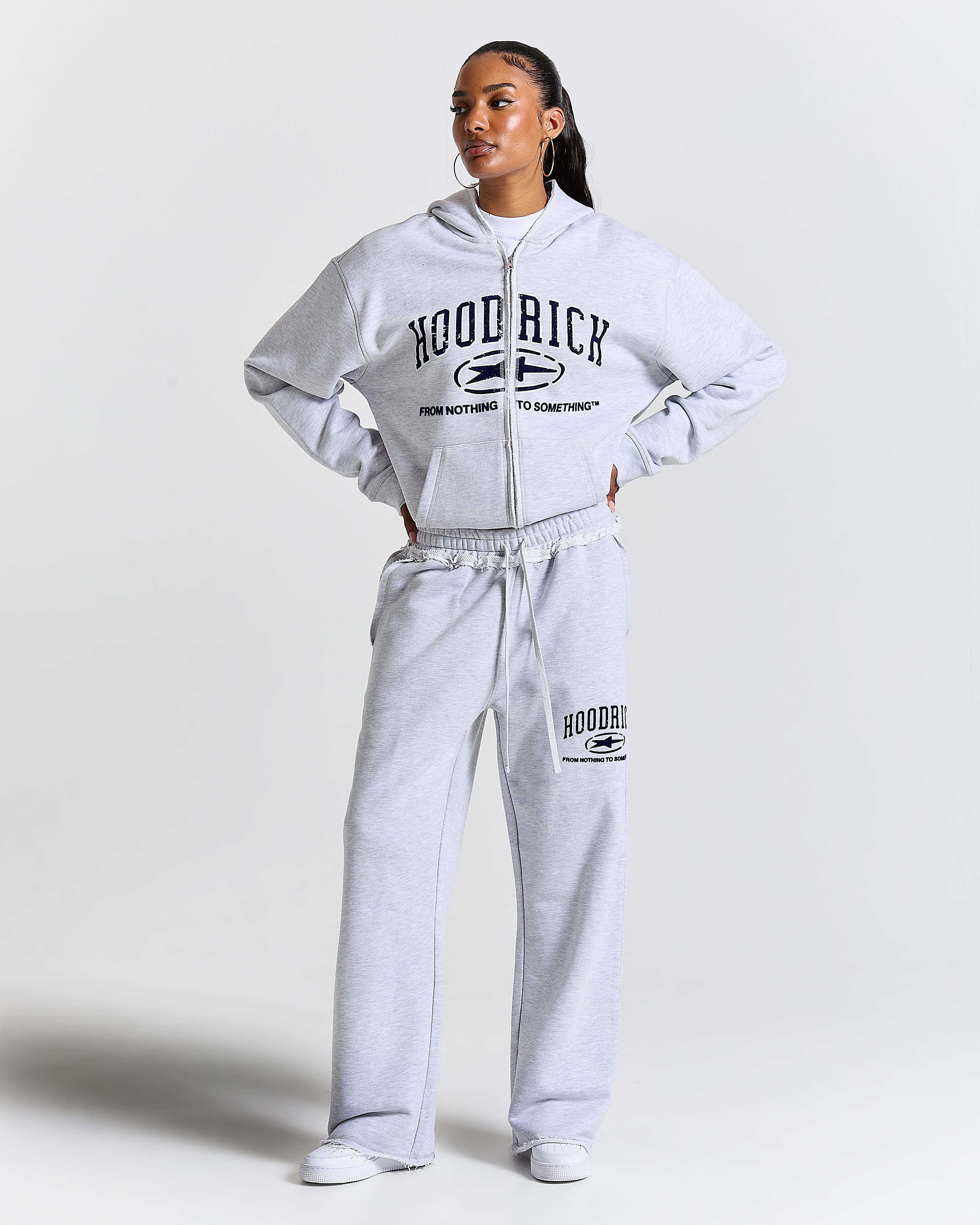 Person wearing a grey 'HoodRich' tracksuit on a white background