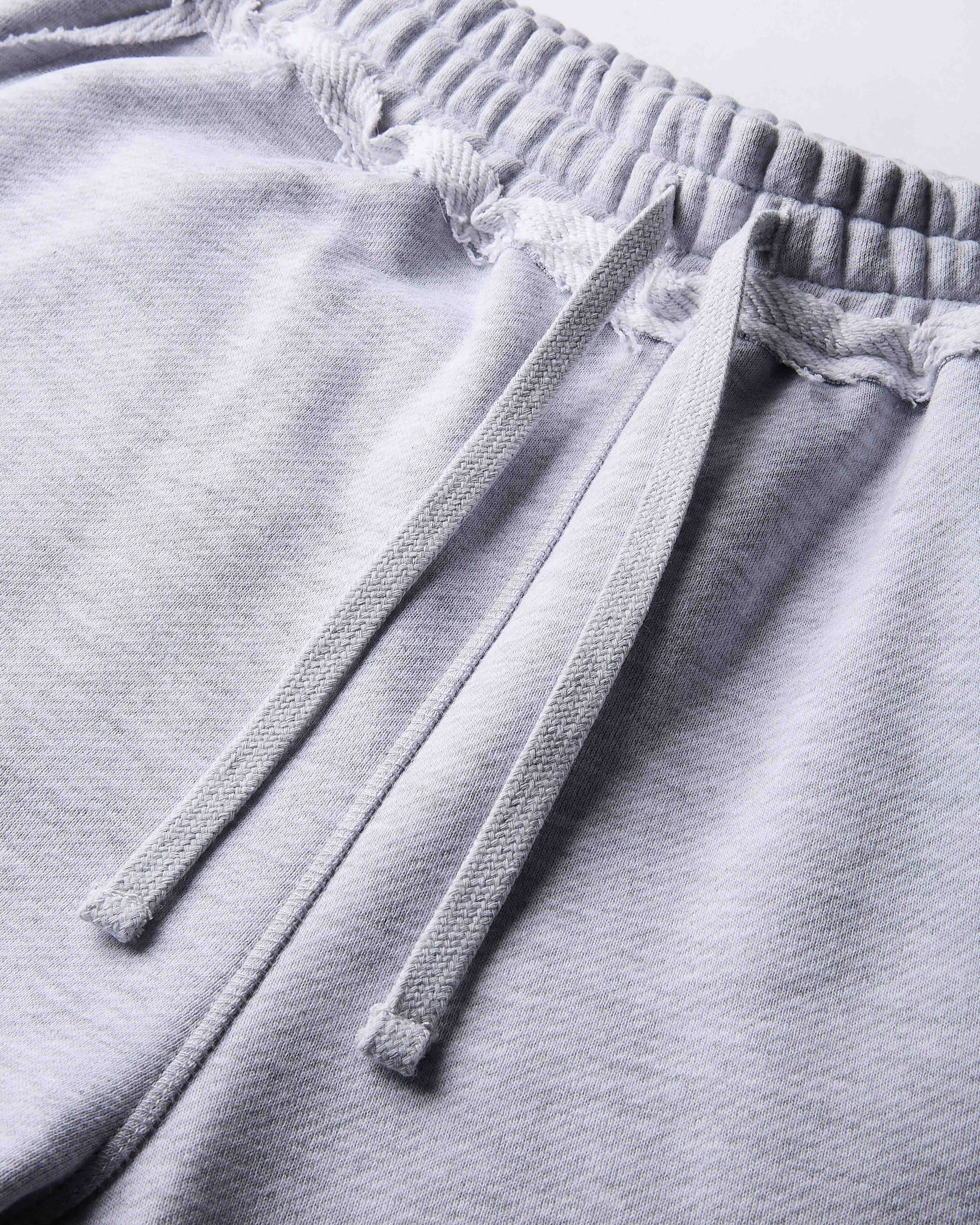 Close-up of gray sweatpants with drawstring on a light gray background