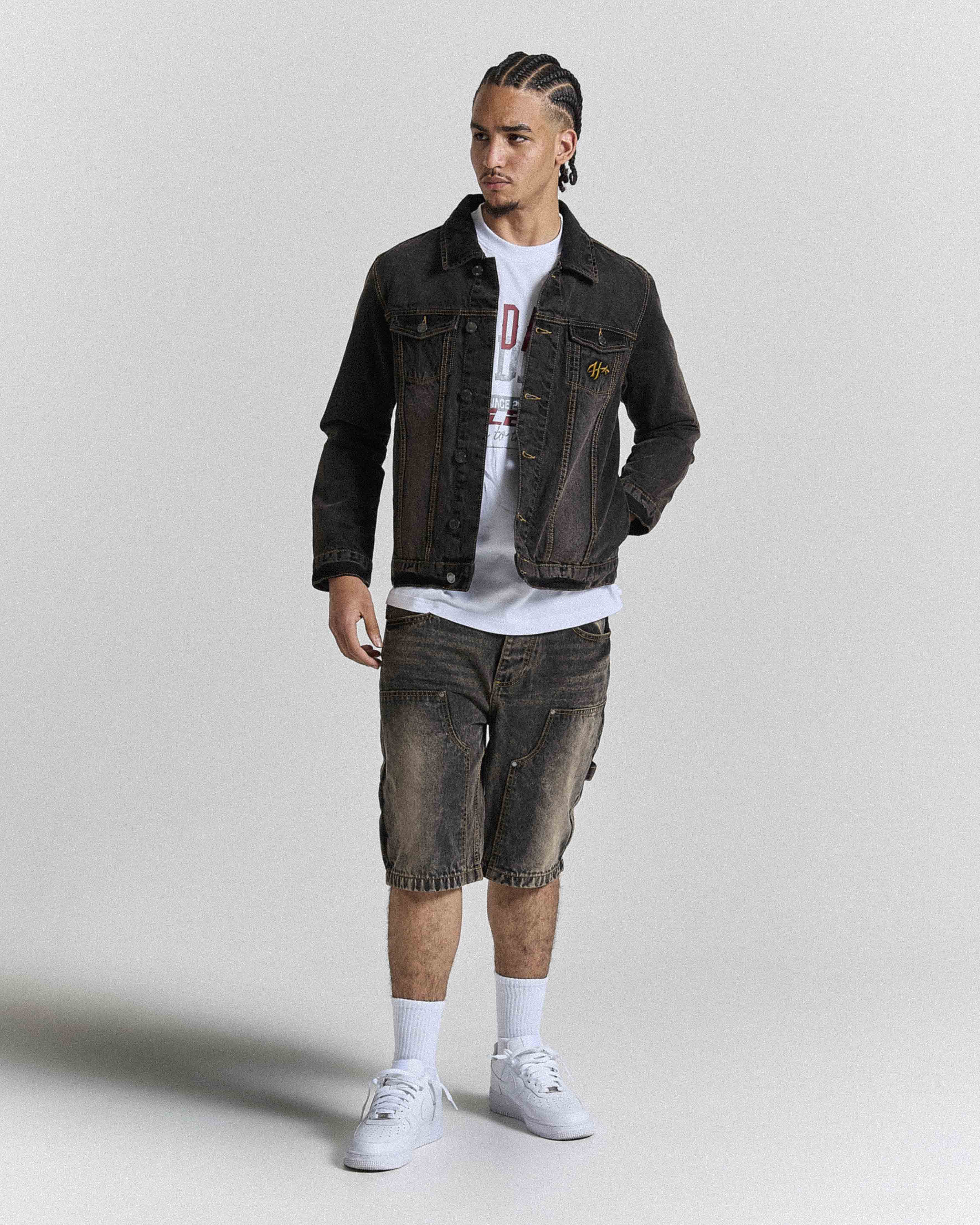 Model wearing regular fit black rust washed denim jorts and a matching jacket.