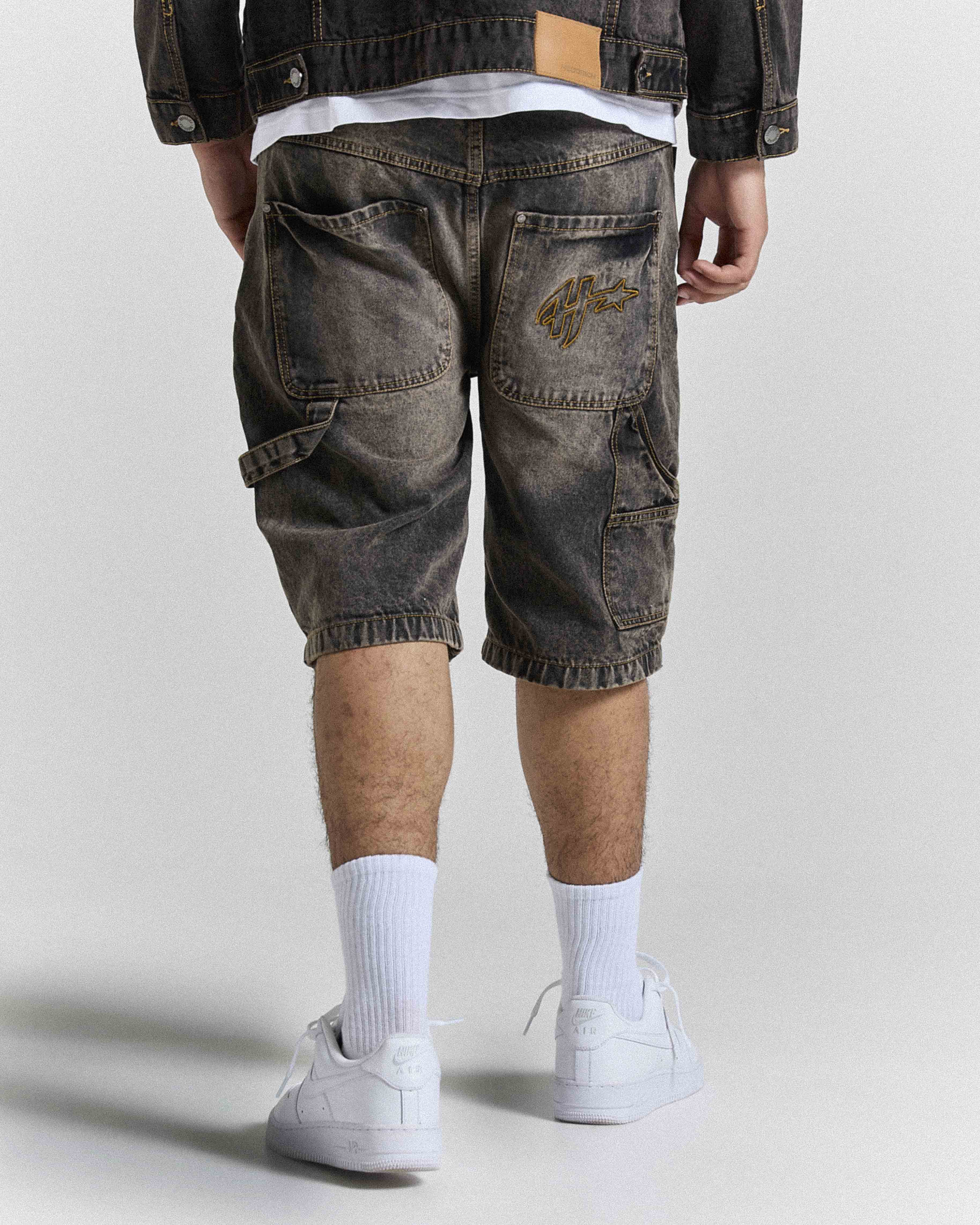 Model seen from behind wearing regular fit black rust washed denim jorts.