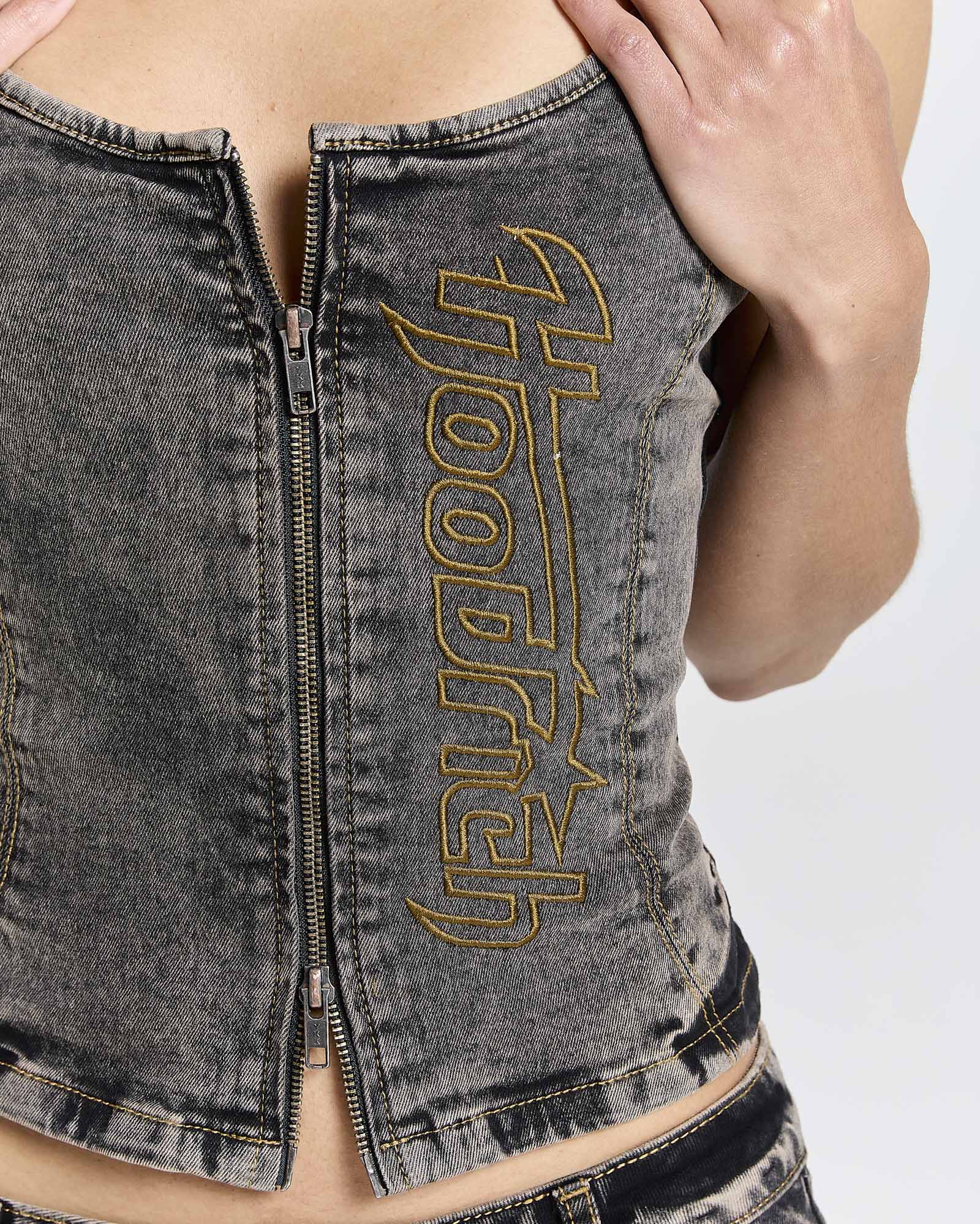 Close-up of the zip front and yellow Hoodrich logo embroidery on a model wearing a fitted black denim corset top.