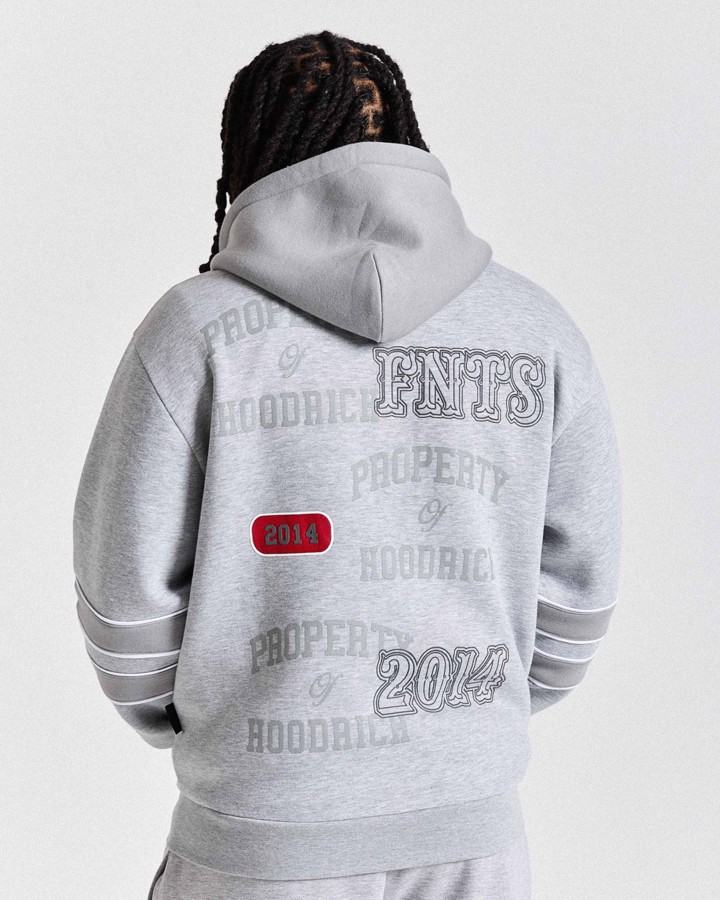 Person wearing a gray hoodie with branding on the back against a white background