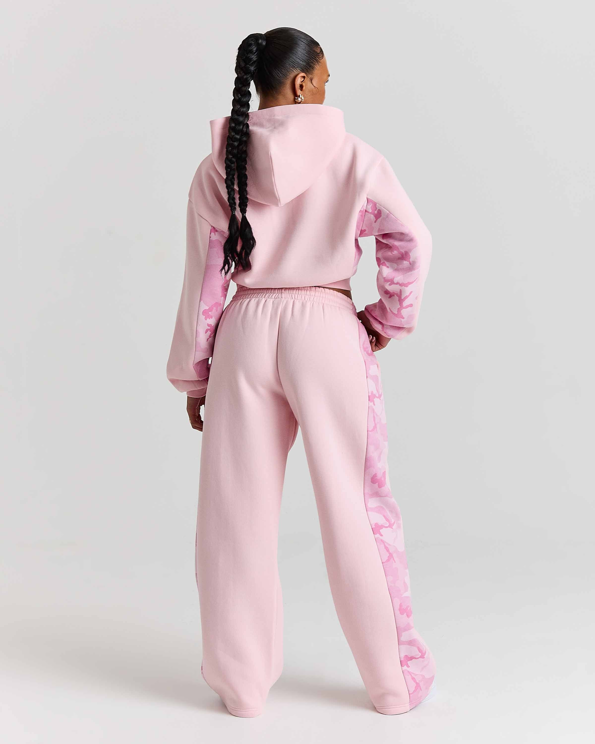 Person wearing a pink tracksuit on a light gray background