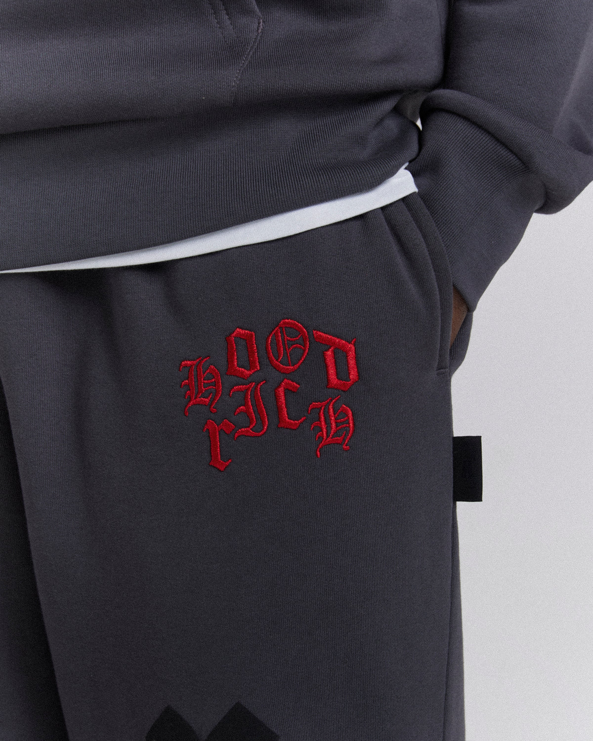 Displays a model wearing the Grey 'Hoodrich' branded men's Crown Full Tracksuit featuring the branding details