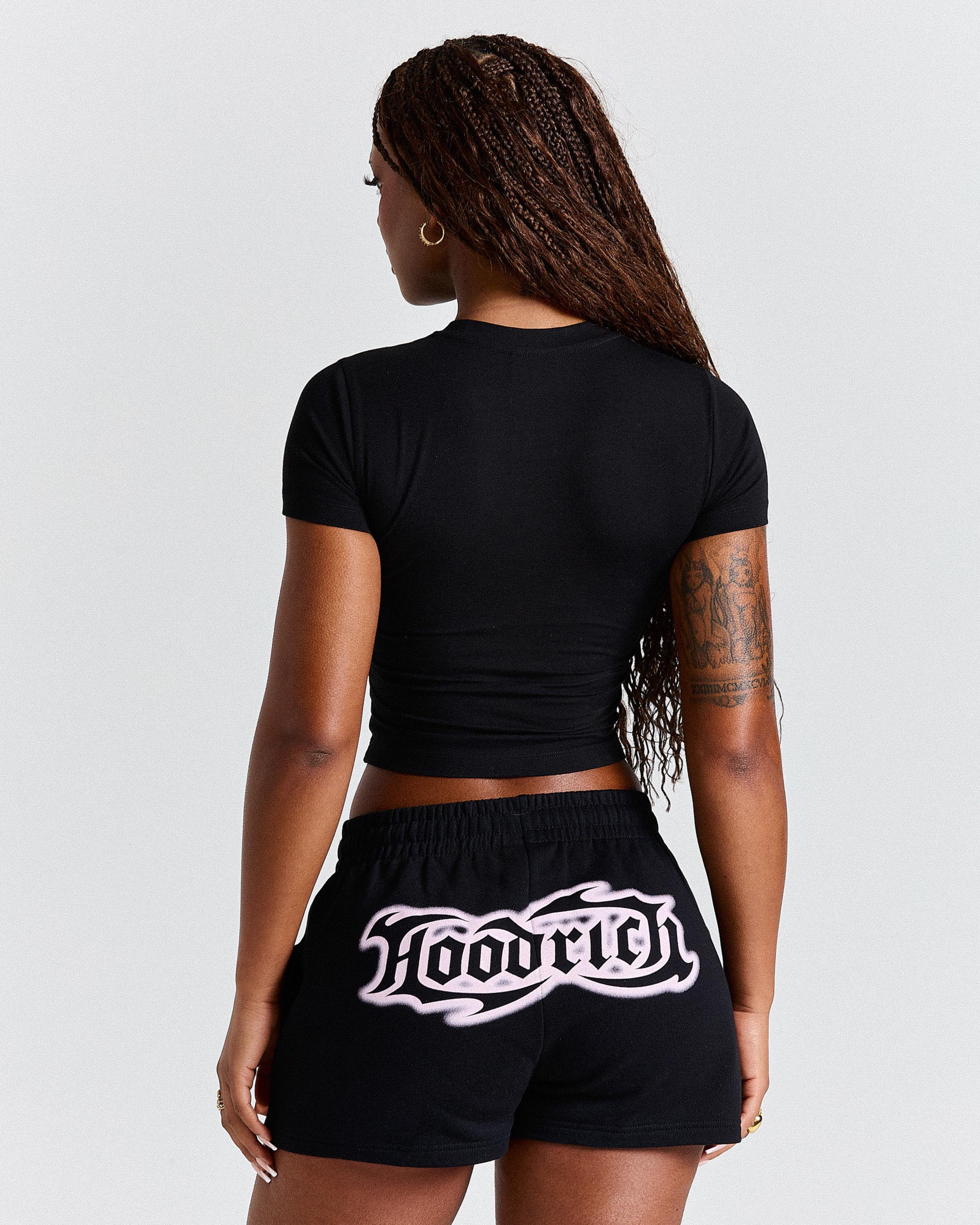 Person wearing a black crop top and black shorts with 'Laoric' branding on a light gray background