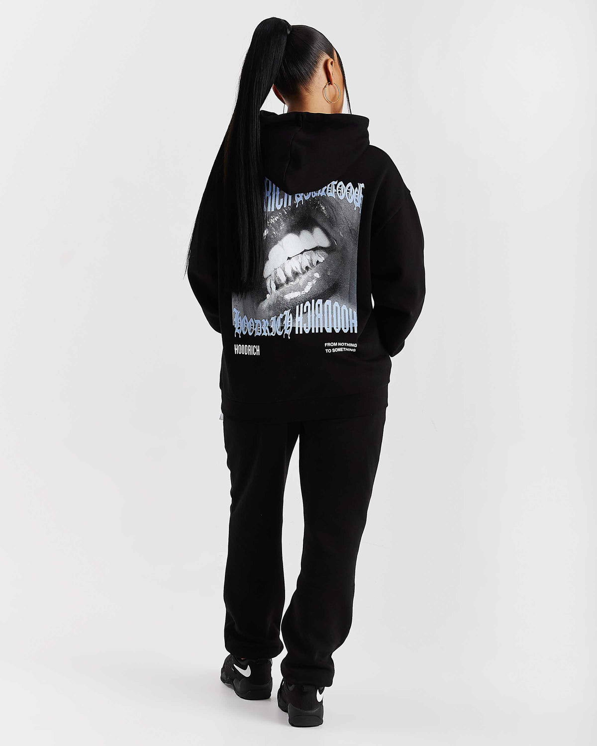 Displays a model wearing the Black 'Hoodrich' branded women's Flex Full Tracksuit