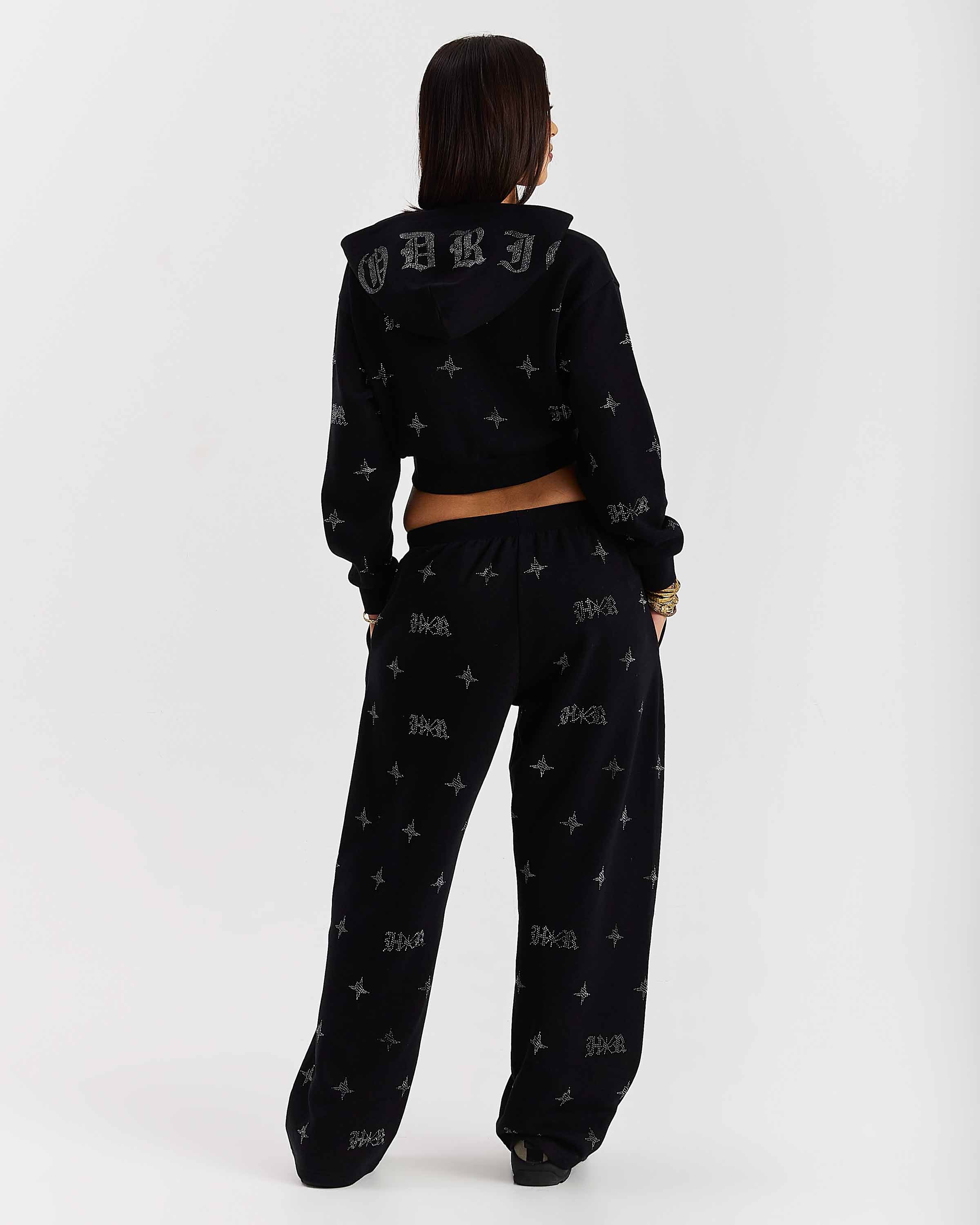 Person wearing a black hoodie and pants with text design on a white background