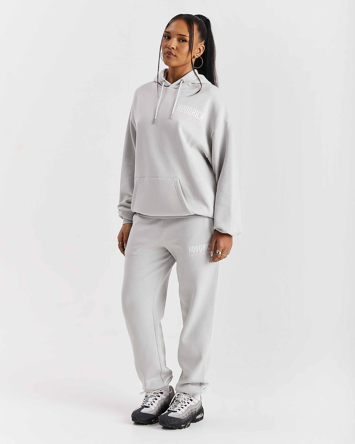 Displays a model wearing the Grey 'Hoodrich' branded women's Flex Full Tracksuit