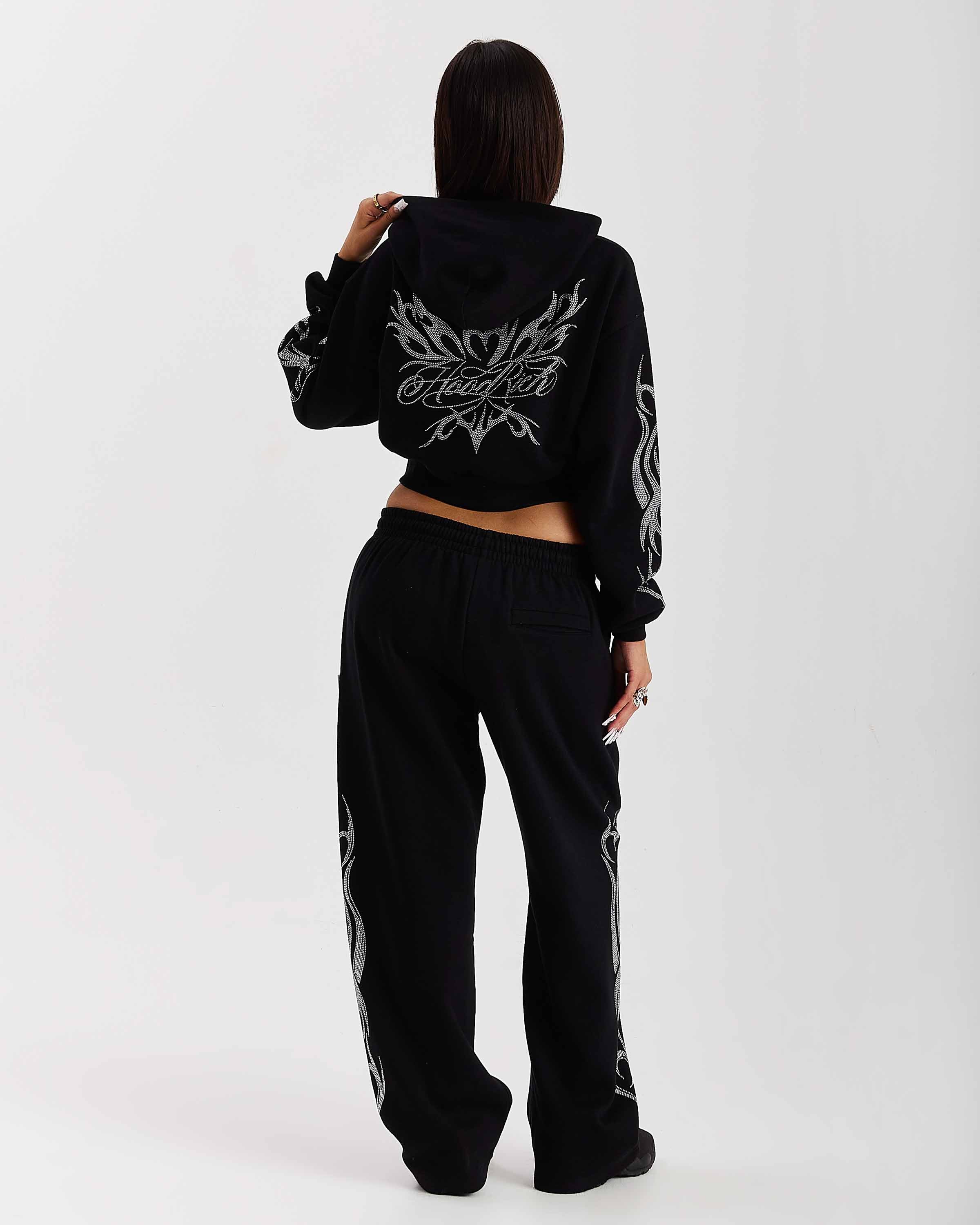 Person wearing a black hoodie and pants with white designs on a white background