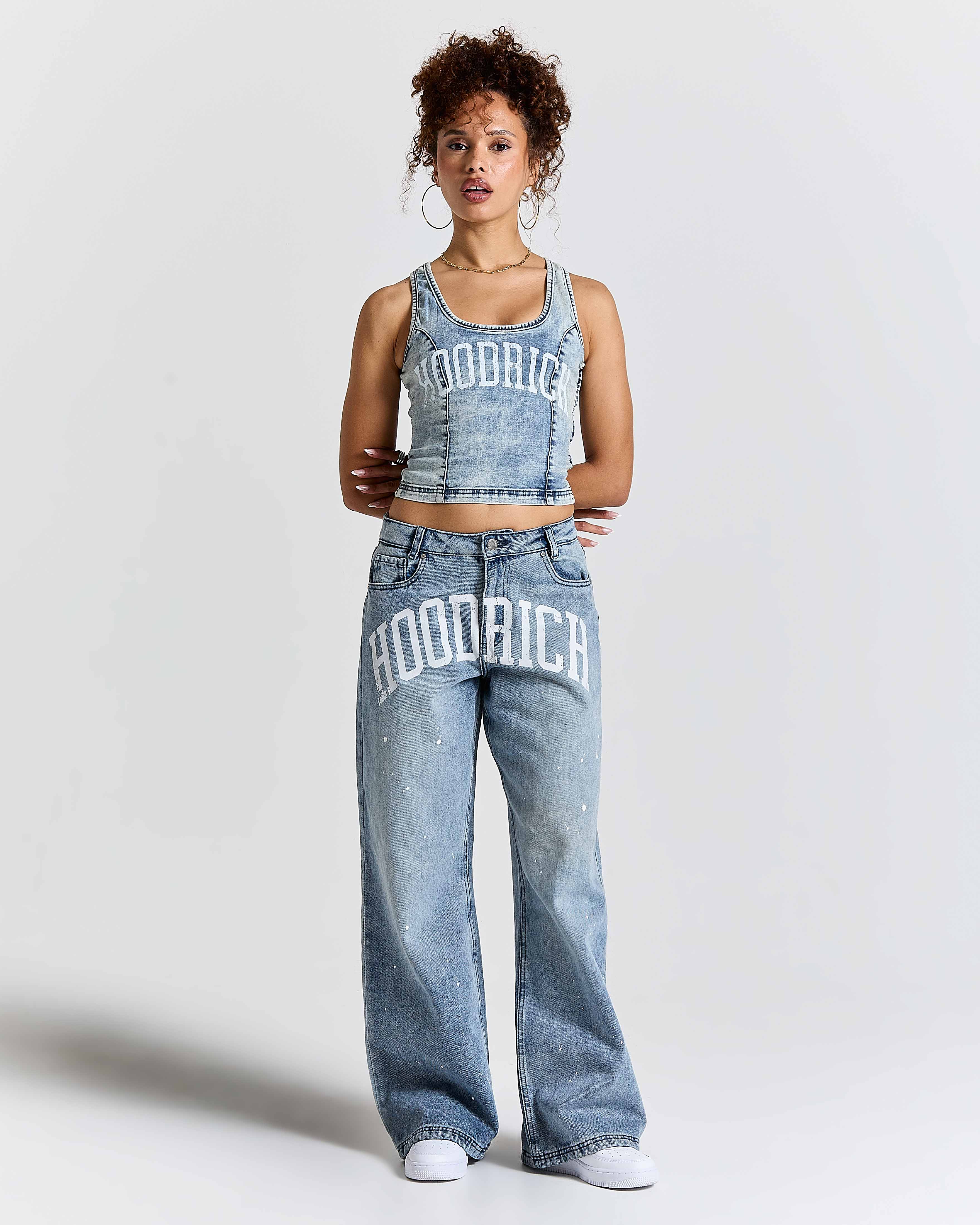 Person wearing a tank top and jeans with 'Hoodrich' branding on a plain background