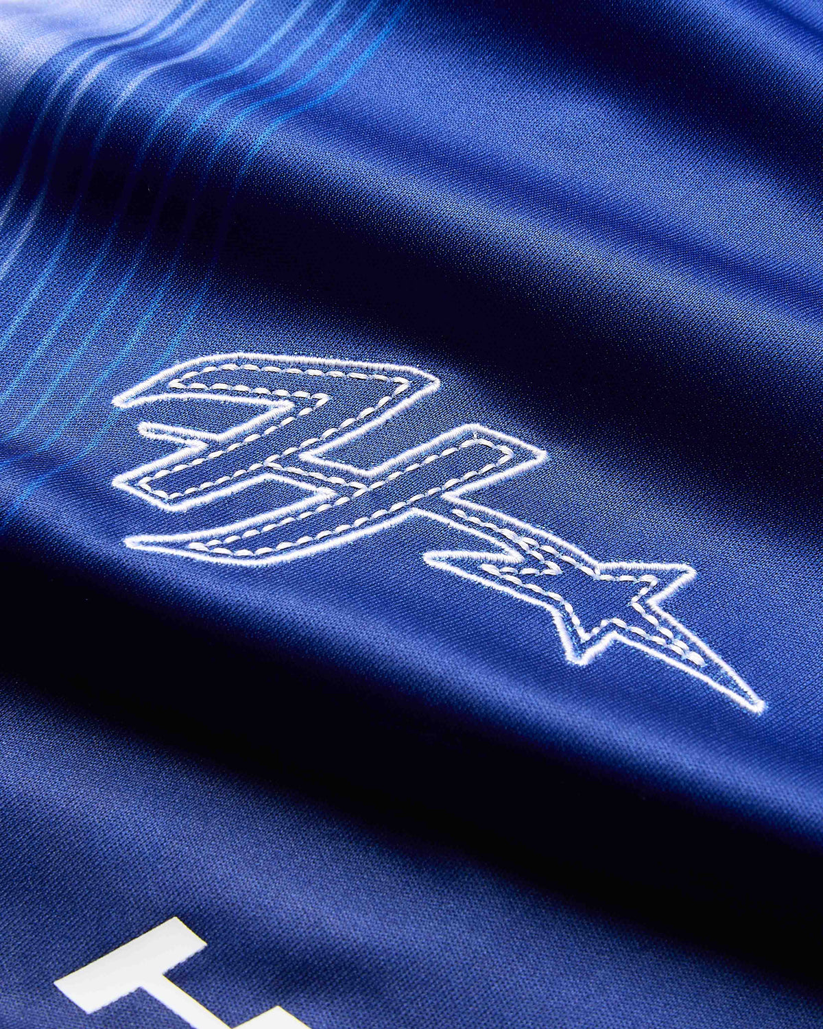 Close-up of a blue fabric with white embroidered logo
