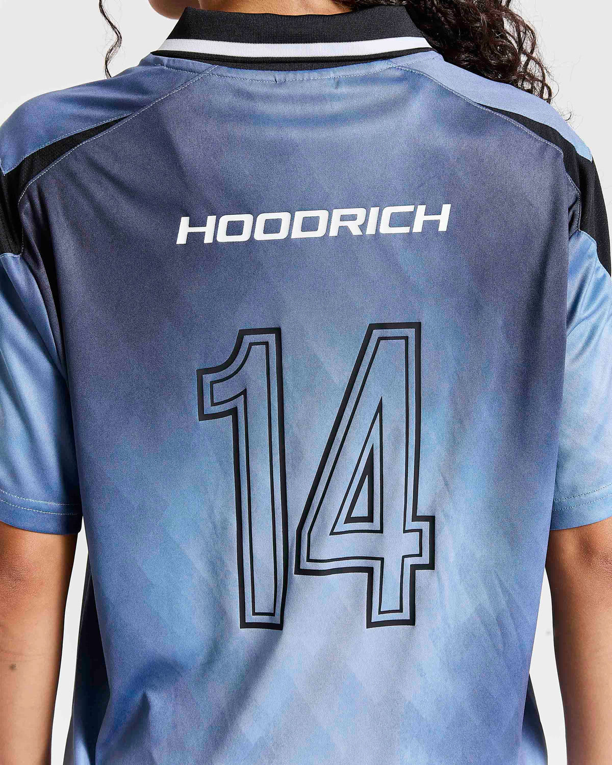 Back view of a light blue and gray soccer jersey with 'HOODRICH' and the number '14' printed on the back, worn by a model.