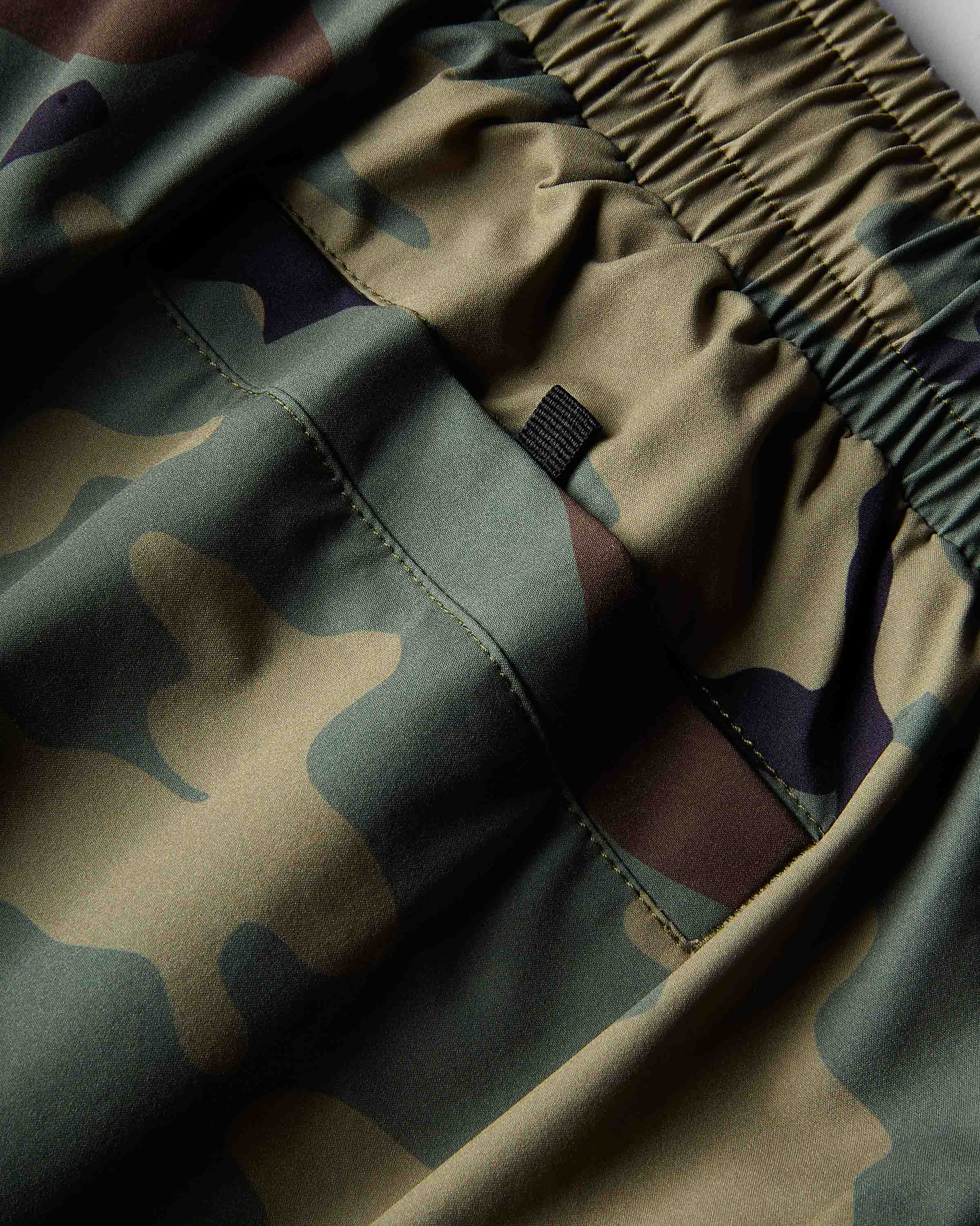Close-up of camouflage-patterned fabric with an elasticized waistband and a small black fabric tag.