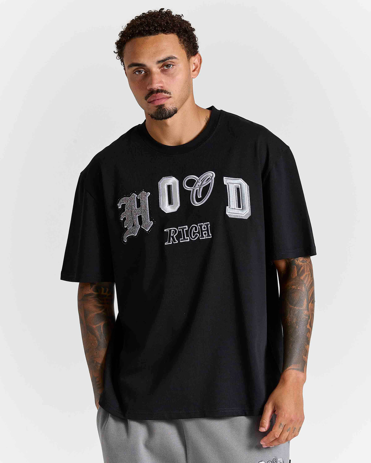Displays a model wearing the Black lava smoke 'Hoodrich' branded Forza Oversized T-shirt 