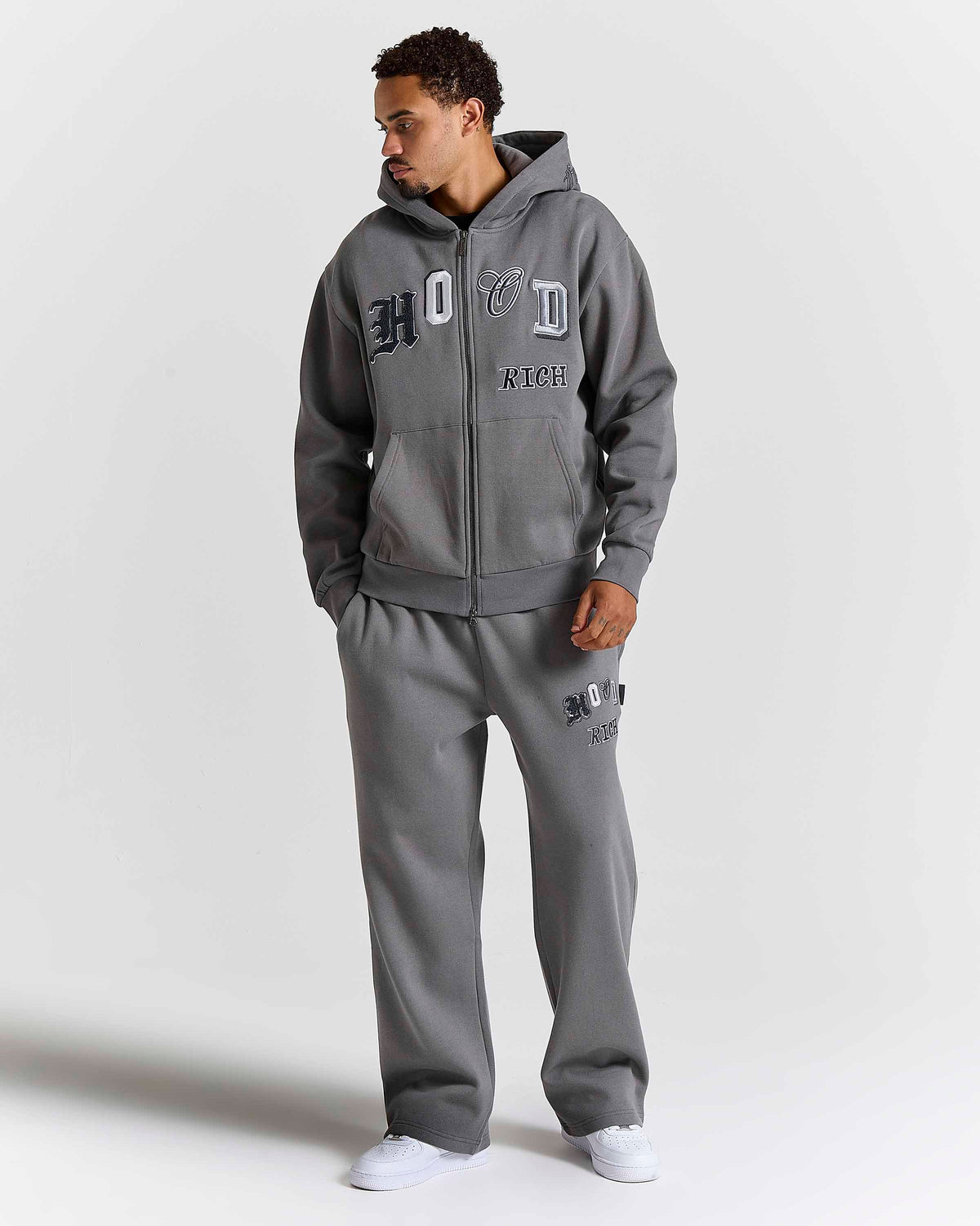 Displays a model wearing the Grey 'Hoodrich' branded men's Forza Full Tracksuit 