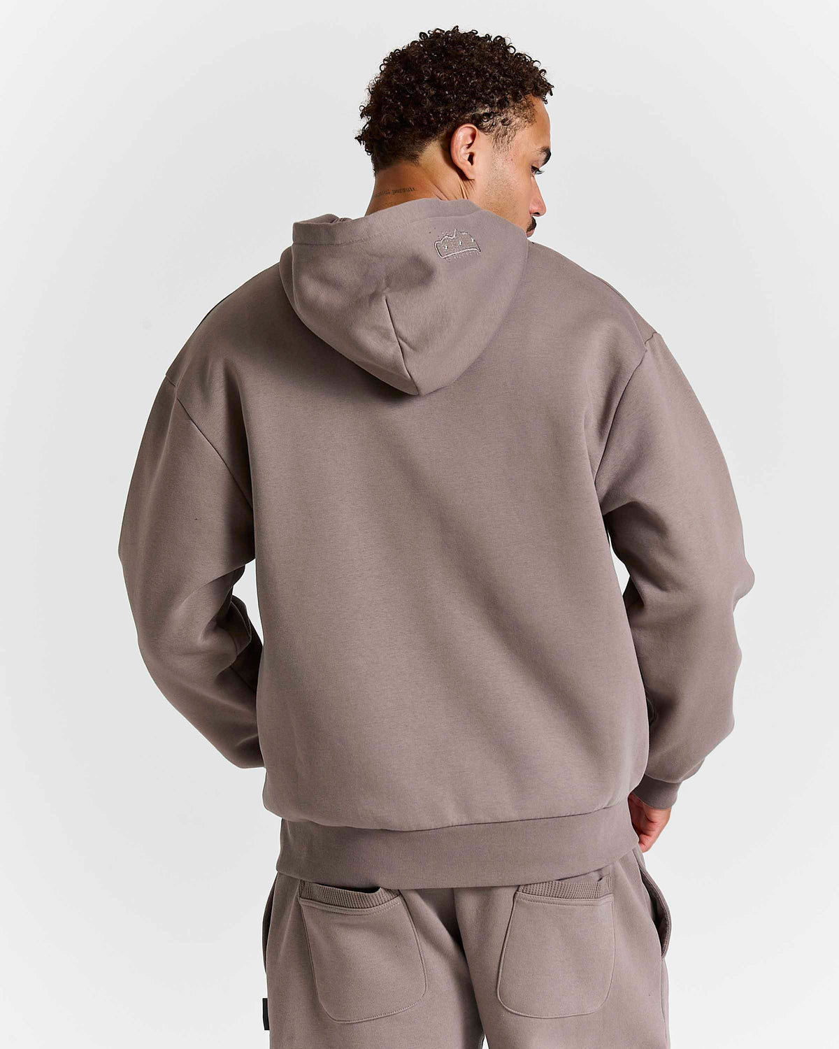 Displays a model wearing the Brown 'Hoodrich' branded men's Varso Studs Full Tracksuit 