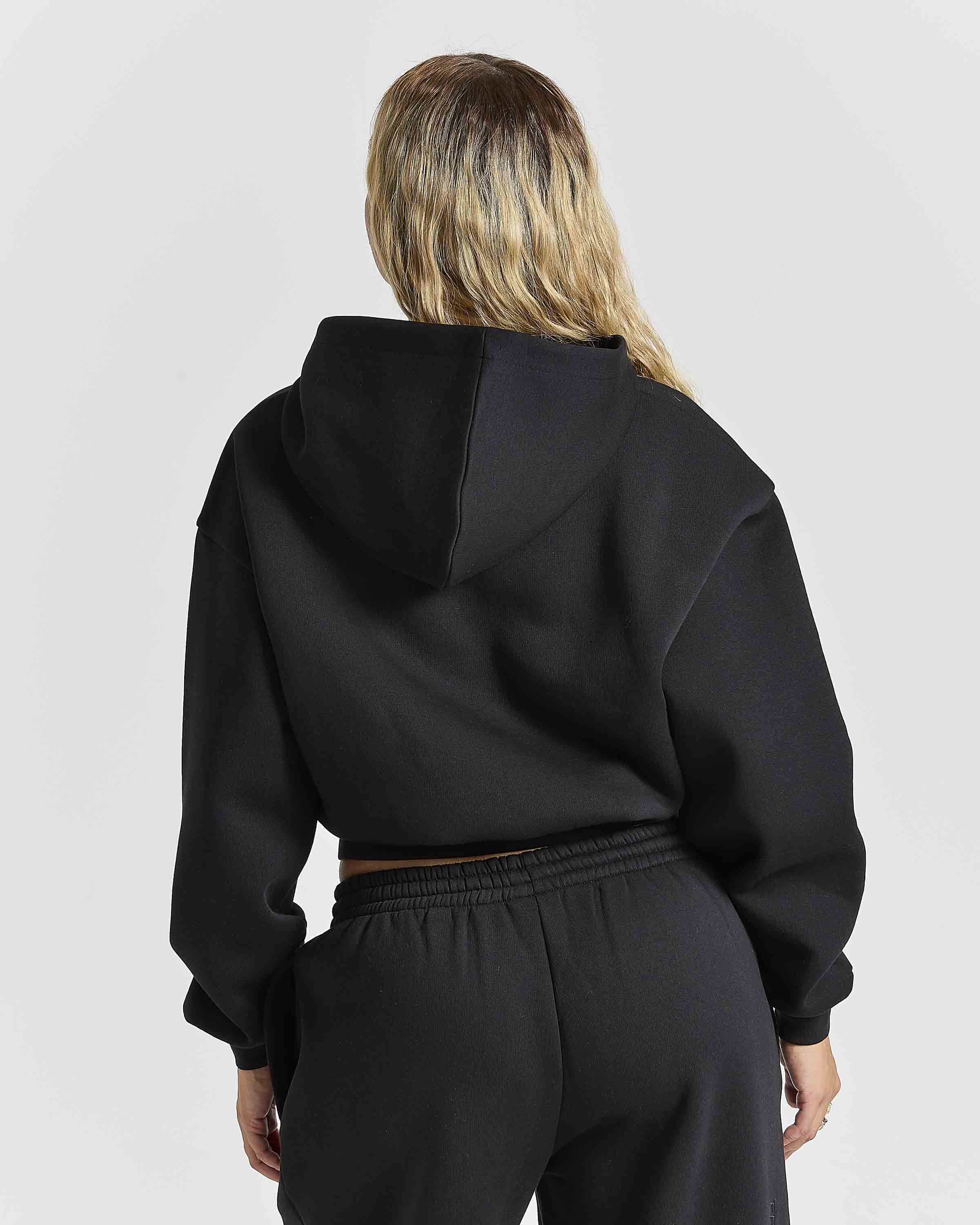 Displays a women wearing the Black 'Hoodrich' branded women's Aegis Full Tracksuit