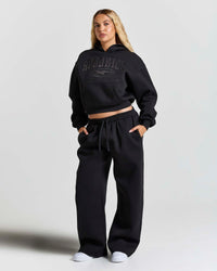 Displays a women wearing the Black 'Hoodrich' branded women's Aegis Full Tracksuit