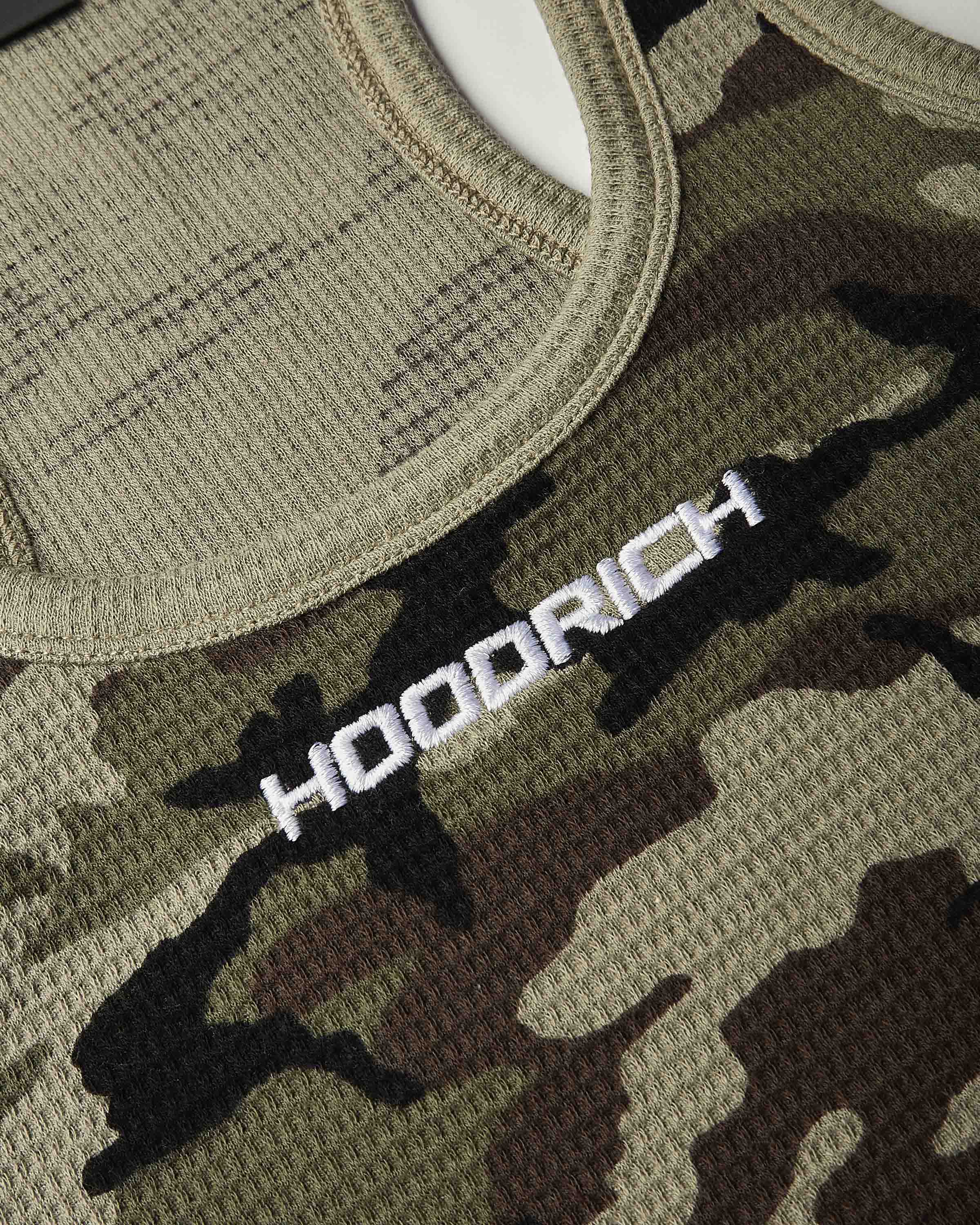 Close-up of a camouflage knit top with a white embroidered 'HOODRICH' logo across the chest.