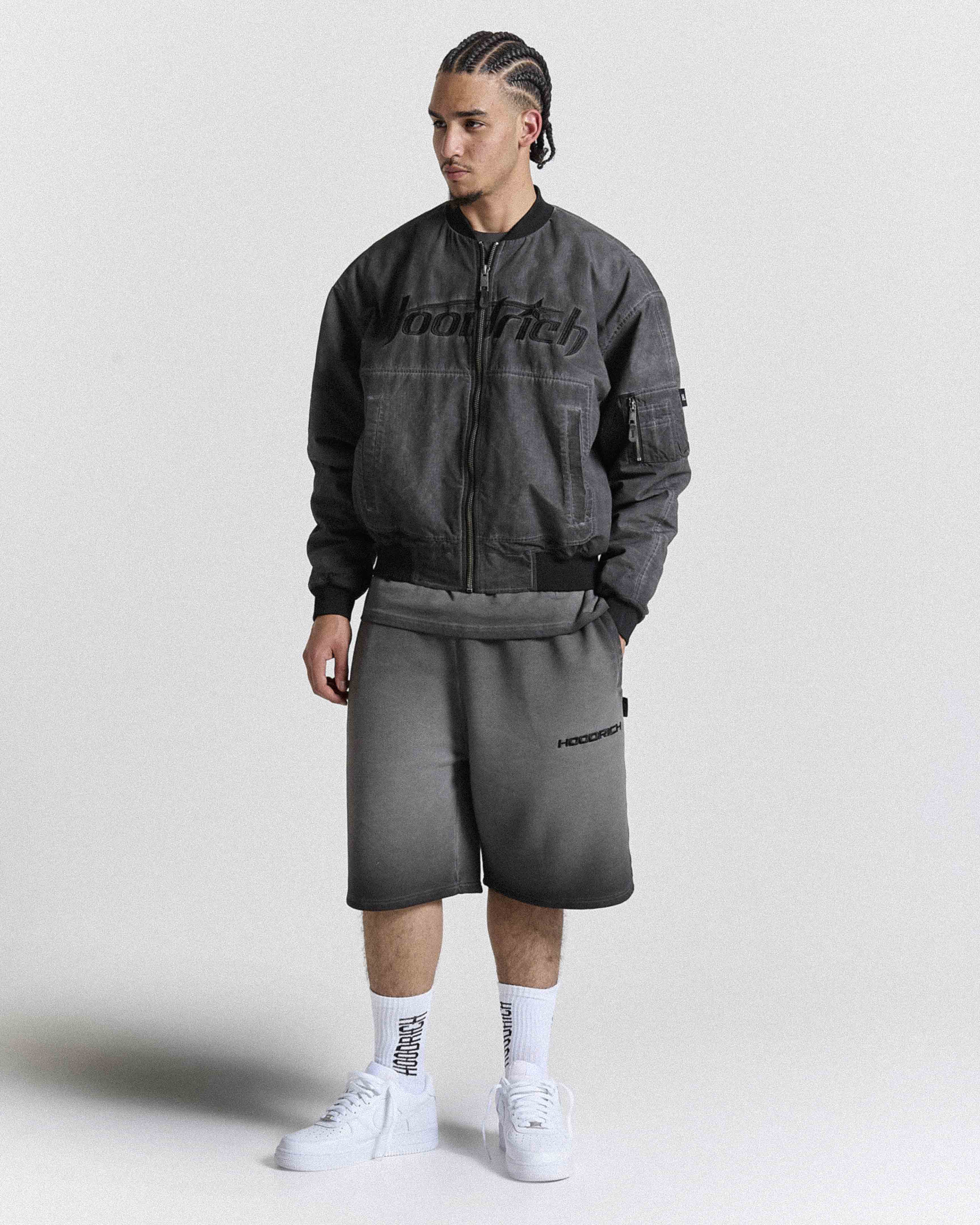Male model wearing a gray jacket and shorts with 'Hoodrich' branding on a white background