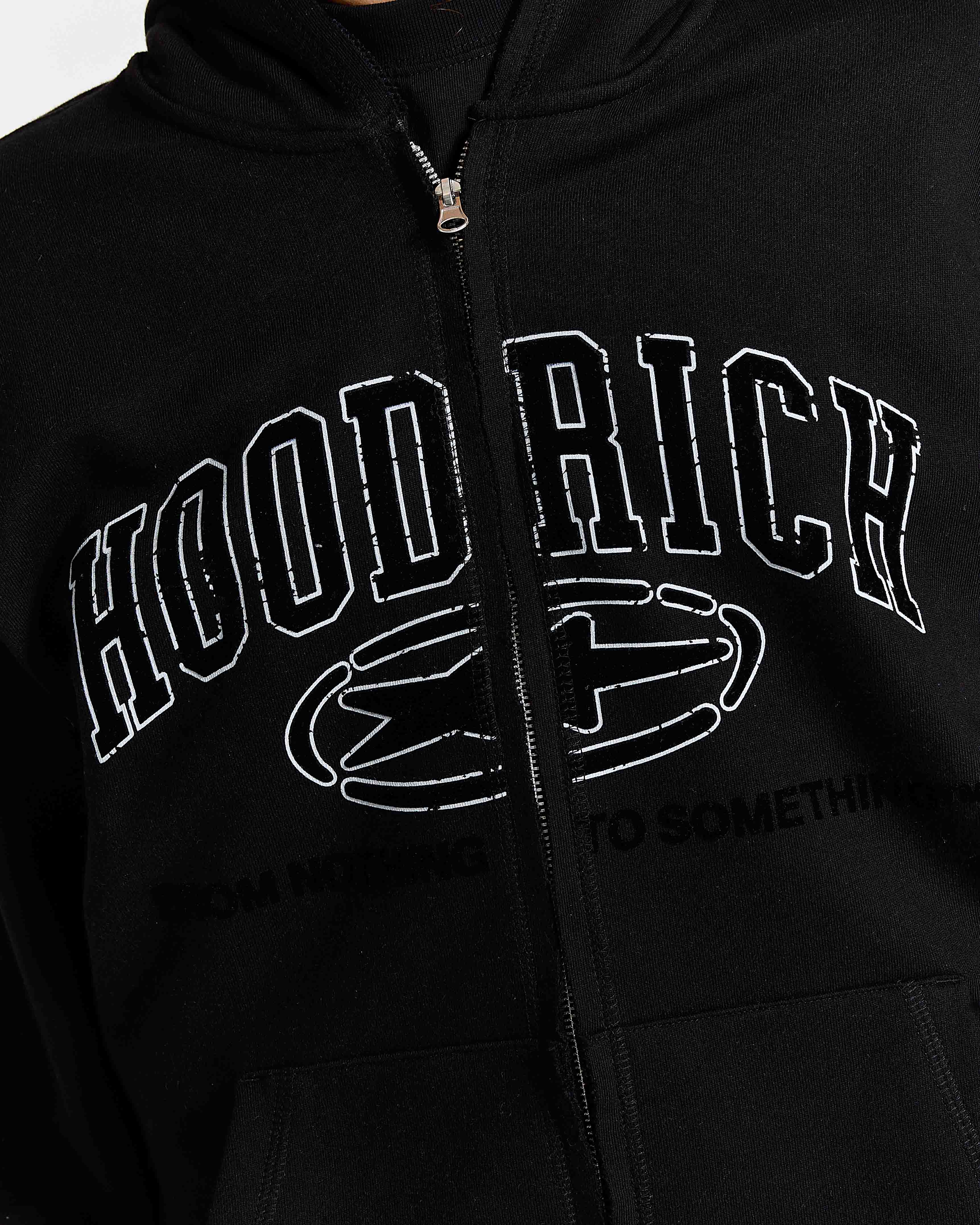 Close-up of a black zip-up hoodie with a distressed white graphic reading 'HOOD RICH' and a stylized emblem on the front.