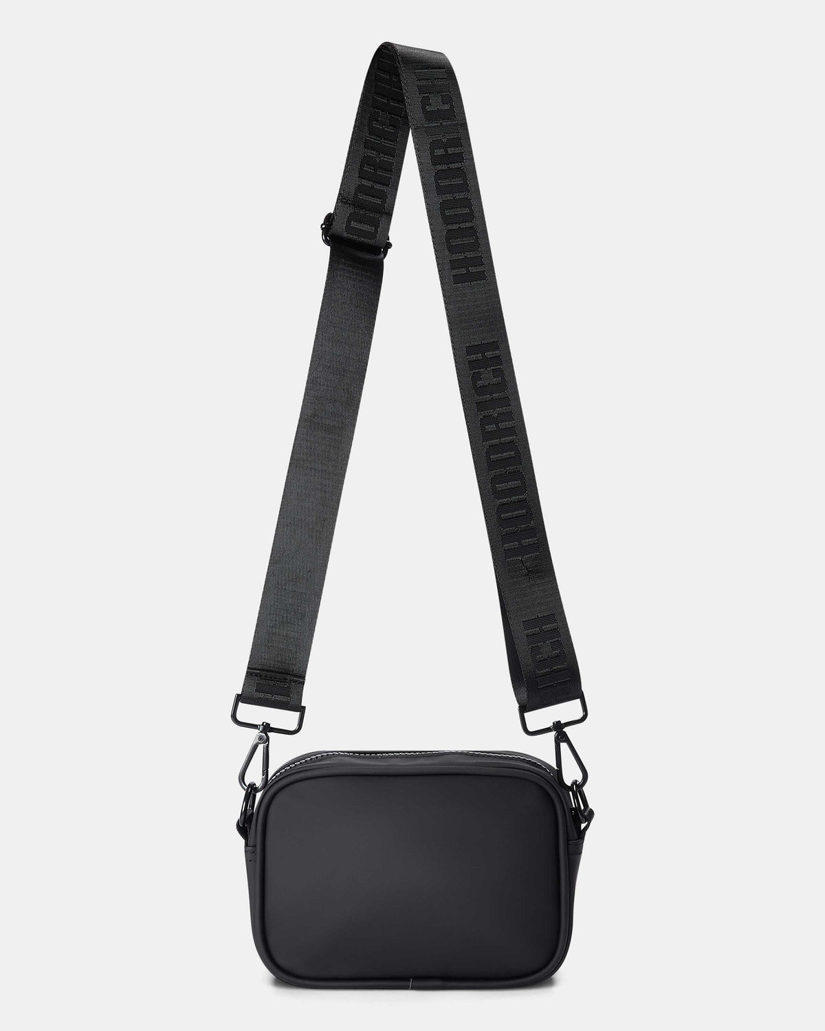 A black nylon crossbody camera bag with a wide, adjustable black webbing strap featuring white brand lettering, shown against a light gray background.