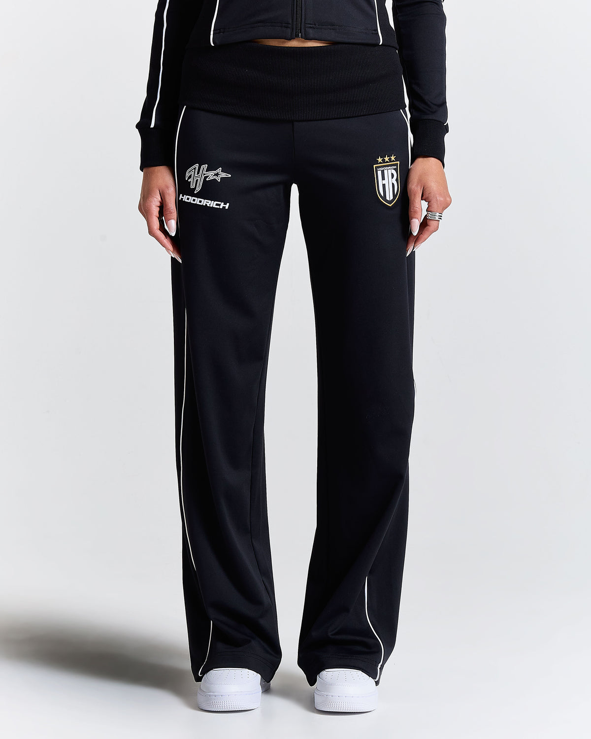 Displays a model wearing the Black 'Hoodrich' branded women's Glide Football Full Tracksuit 