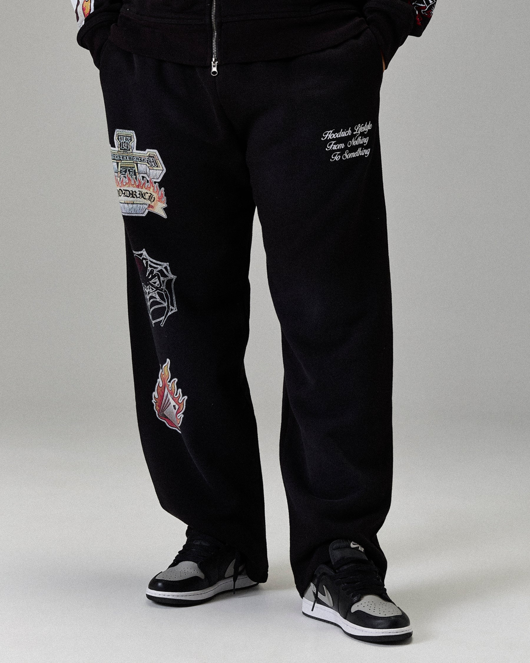 Black pants with various patches on a gray background