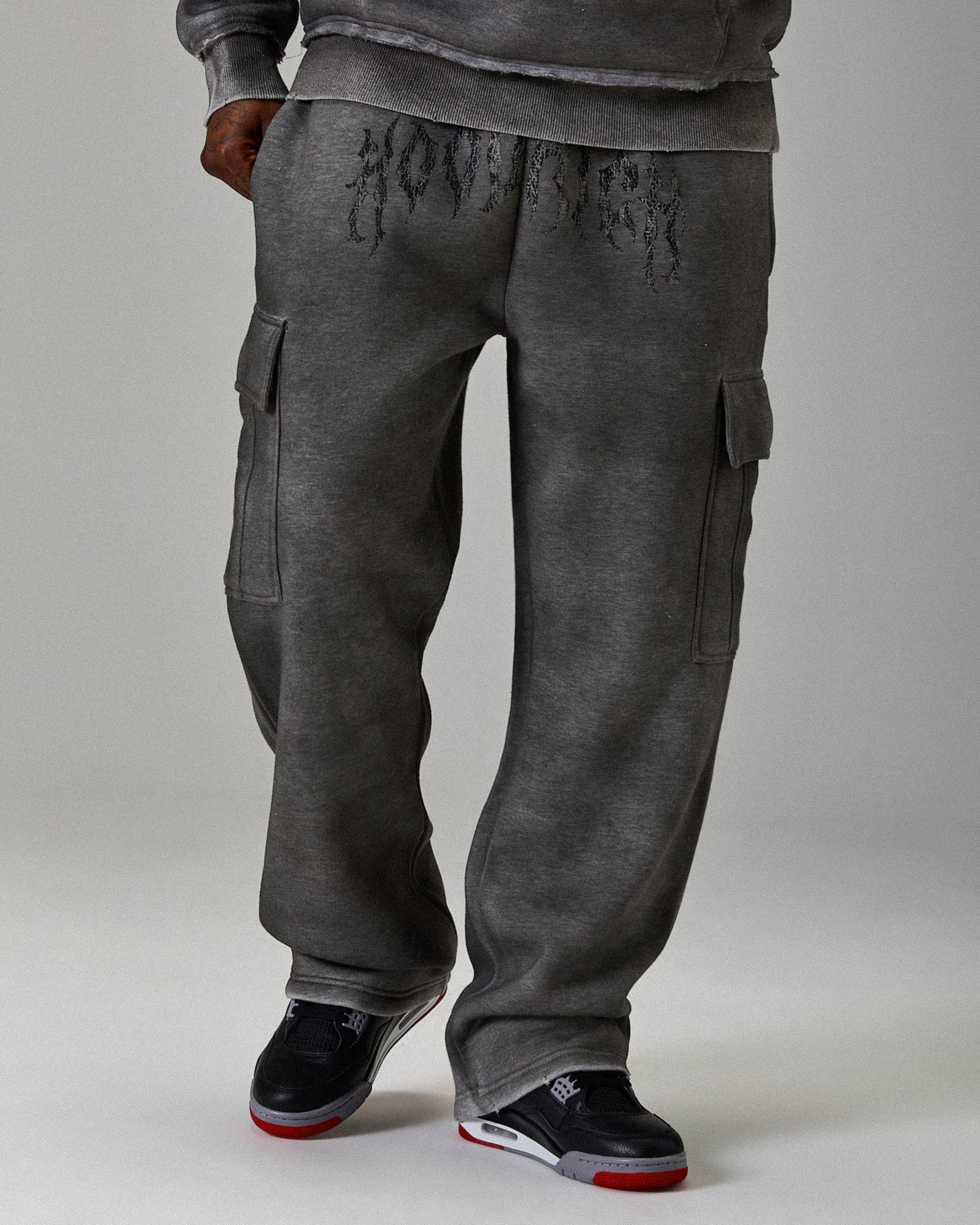 Gray cargo pants with text design on a plain background