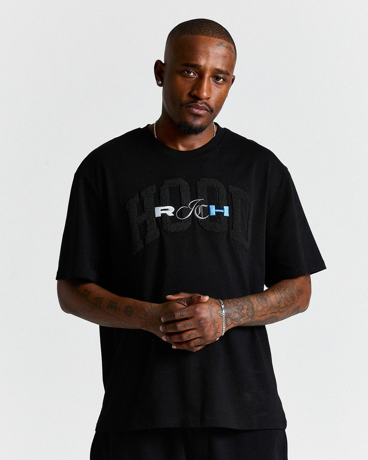 Man wearing a black t-shirt with a logo on a plain background