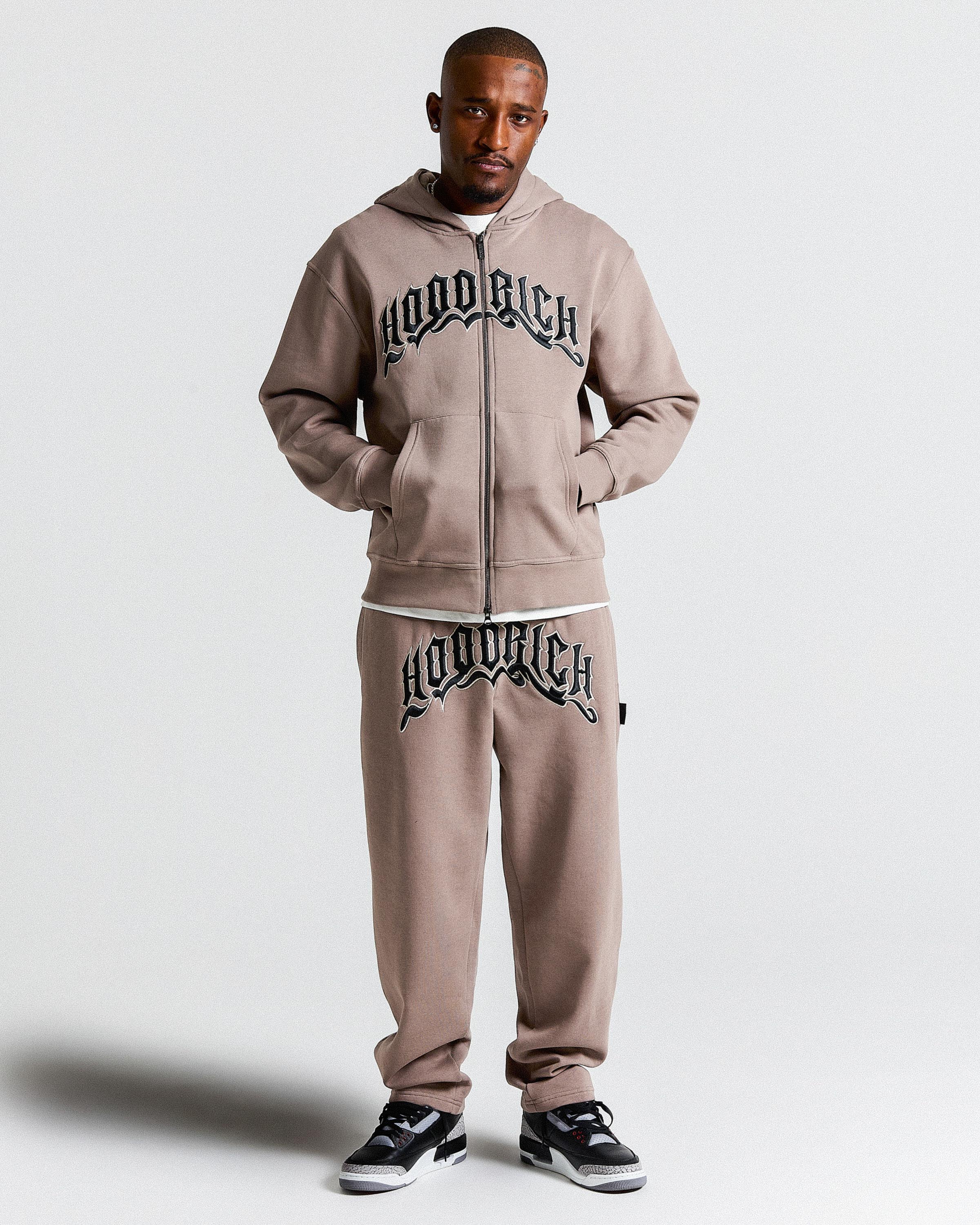 Man wearing a 'Hoodrich' tracksuit on a white background