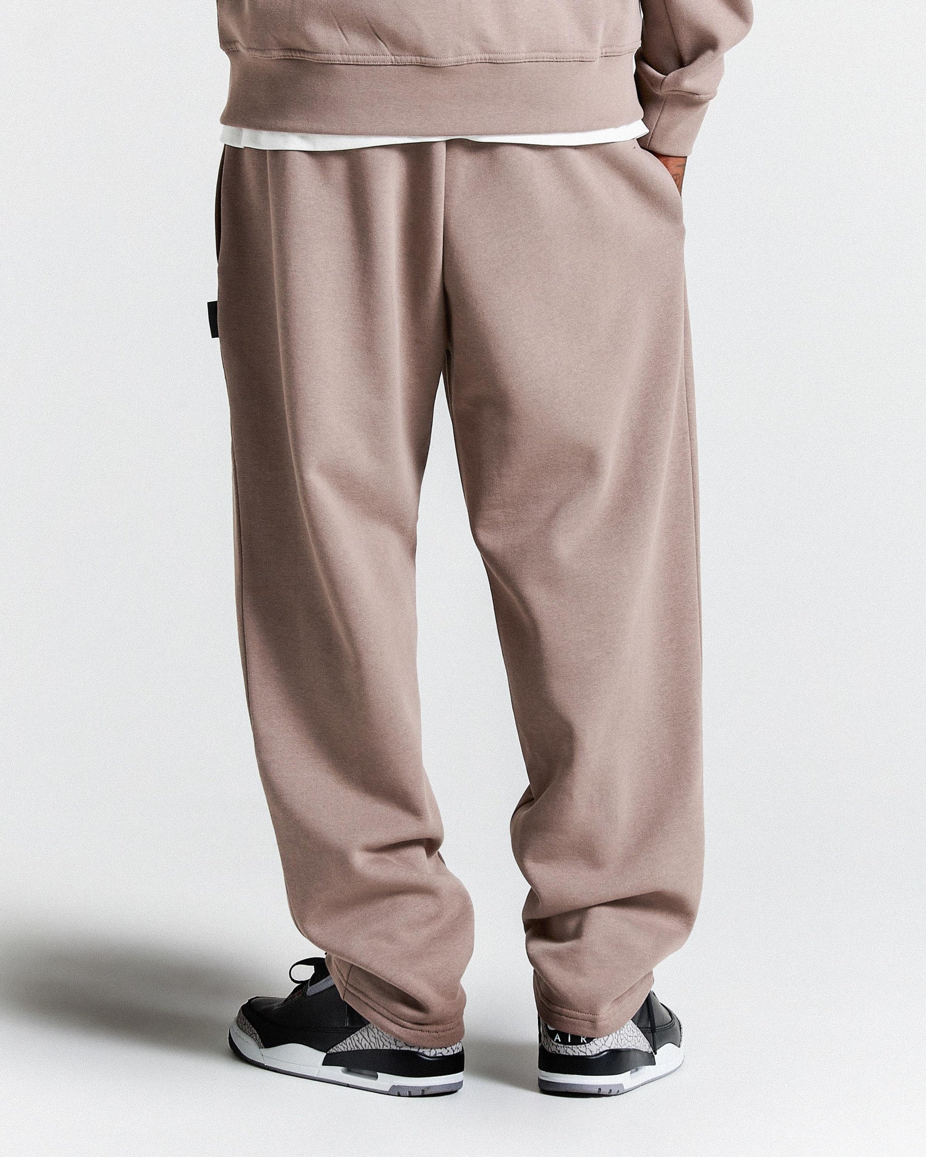 Brown tracksuit with black and white sneakers on a light grey background