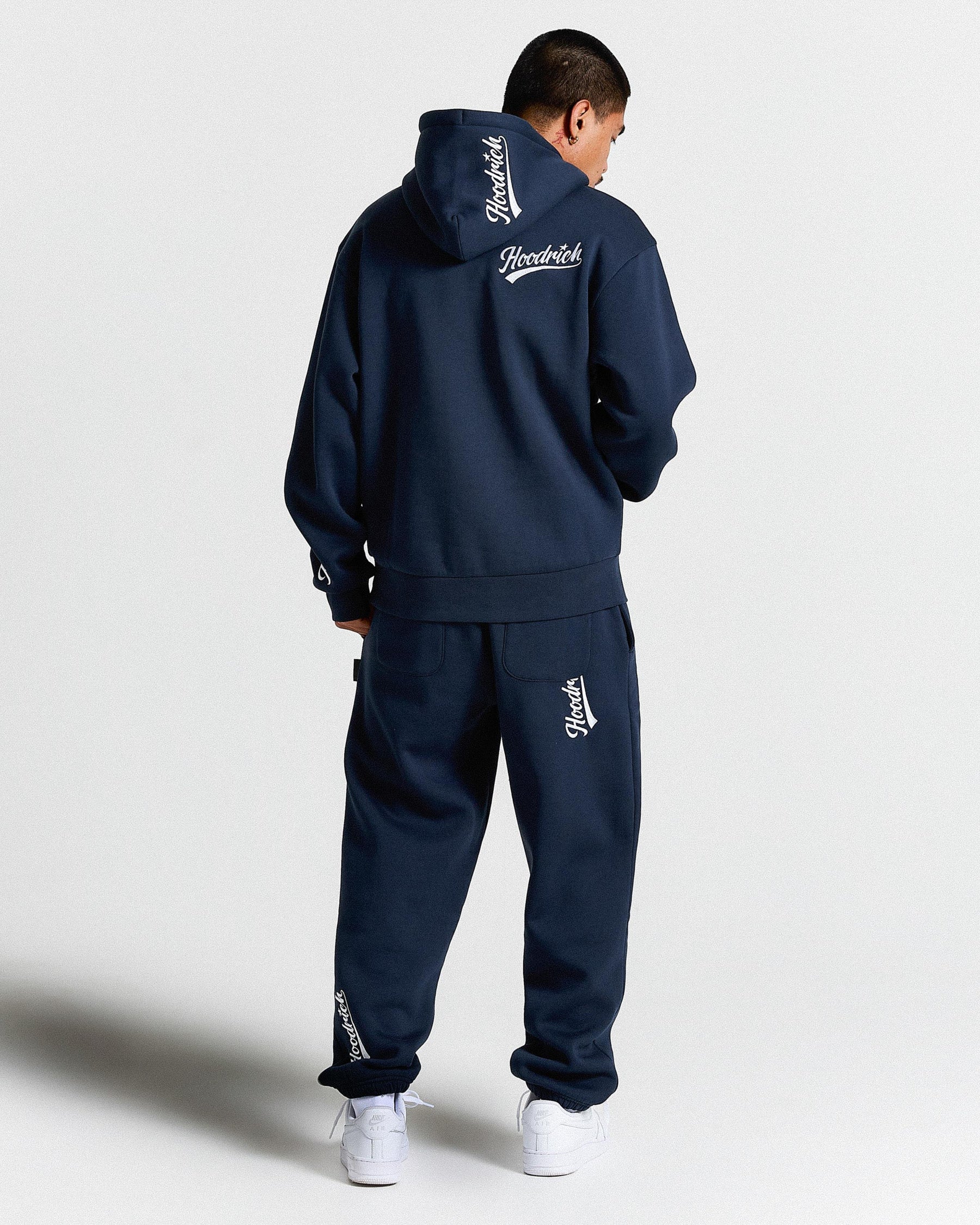 Person wearing a navy tracksuit with branding on a white background
