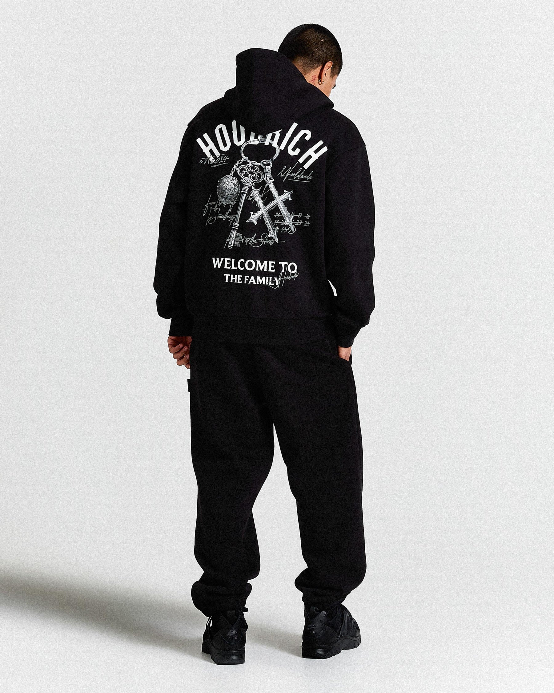 Person wearing a black hoodie with text and graphics on the back against a white background