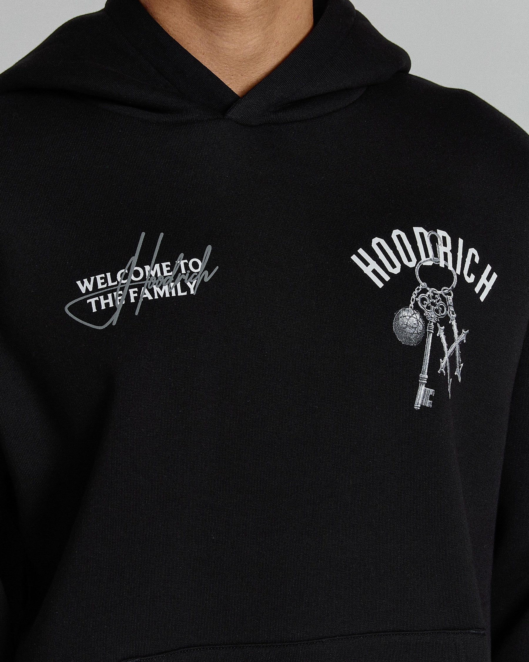 Black hoodie with embroidered text and graphics on a gray background