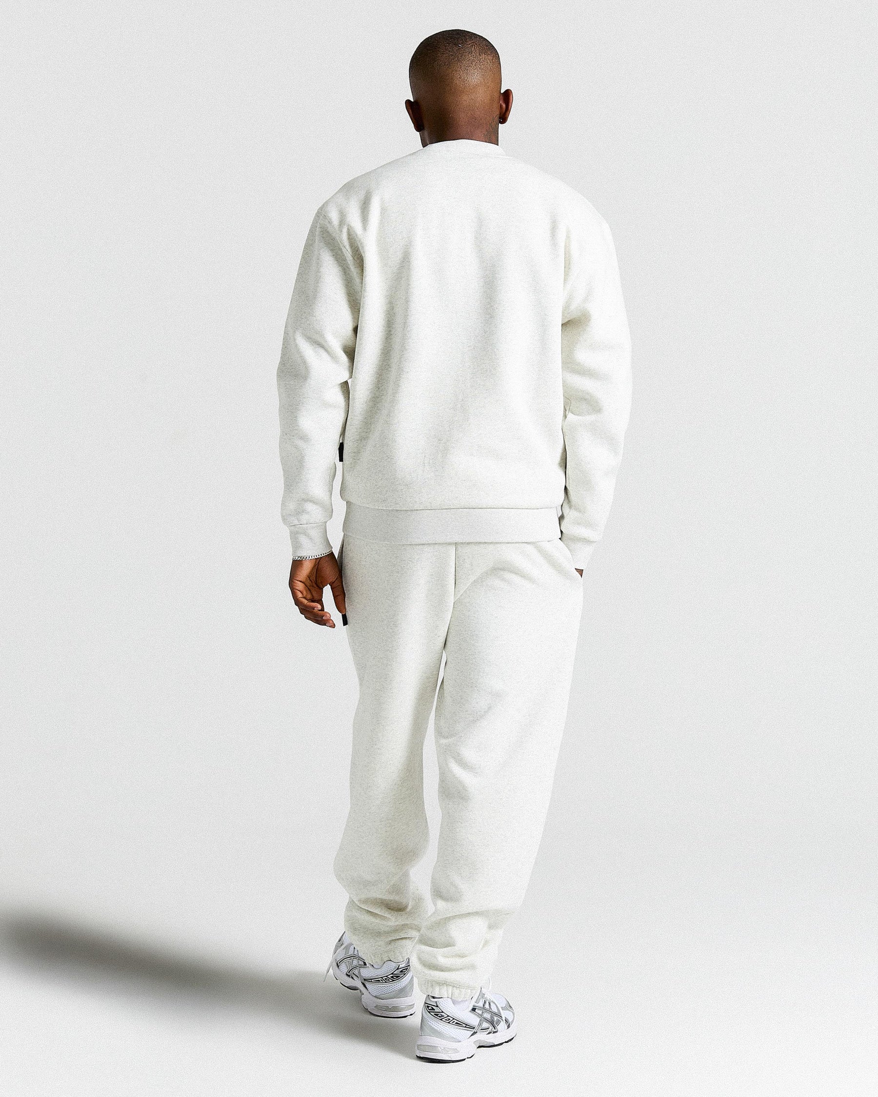 Person wearing a light grey tracksuit on a plain background