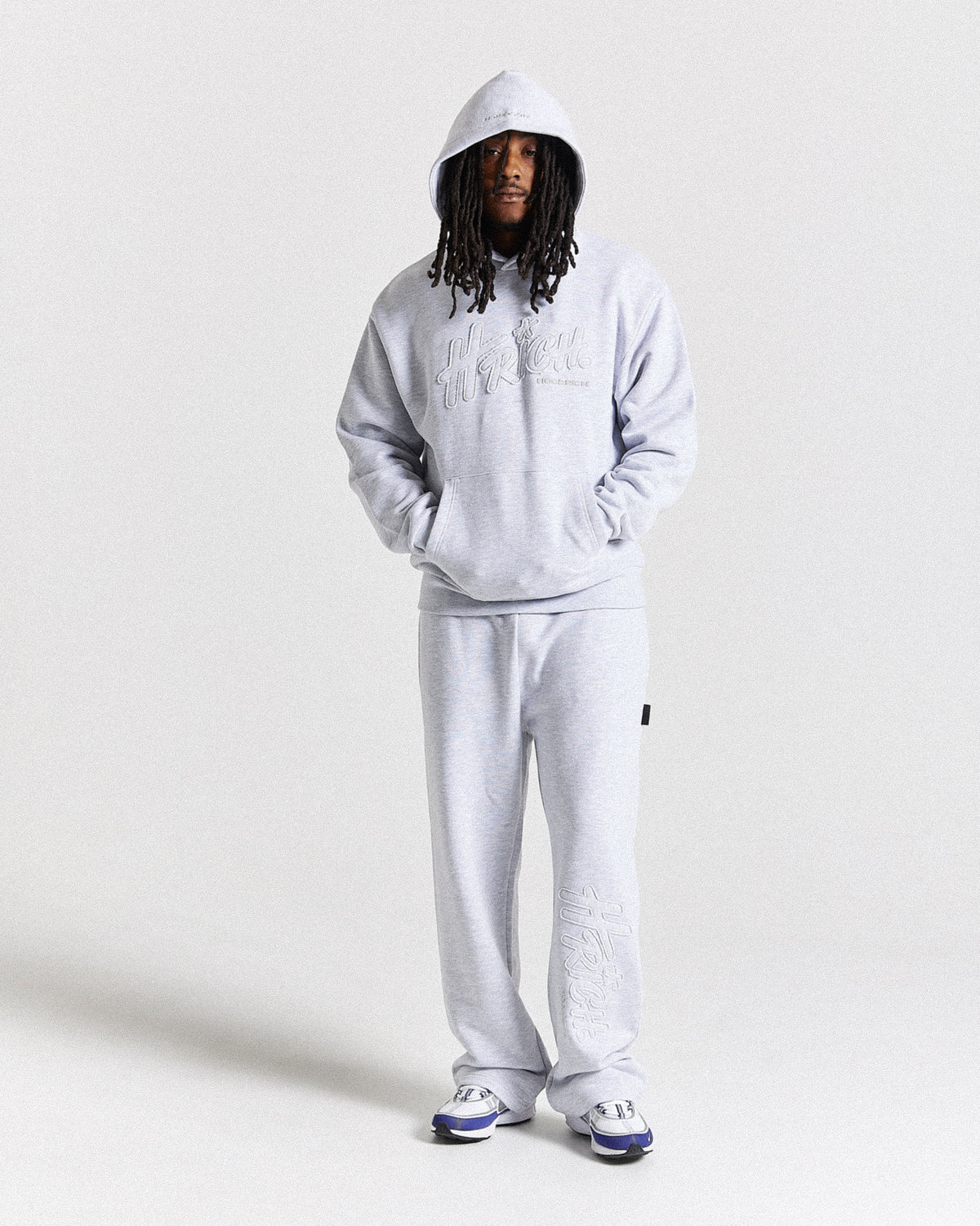 Displays a model wearing the light grey 'Hoodrich' branded men's Asthrich Full Tracksuit 