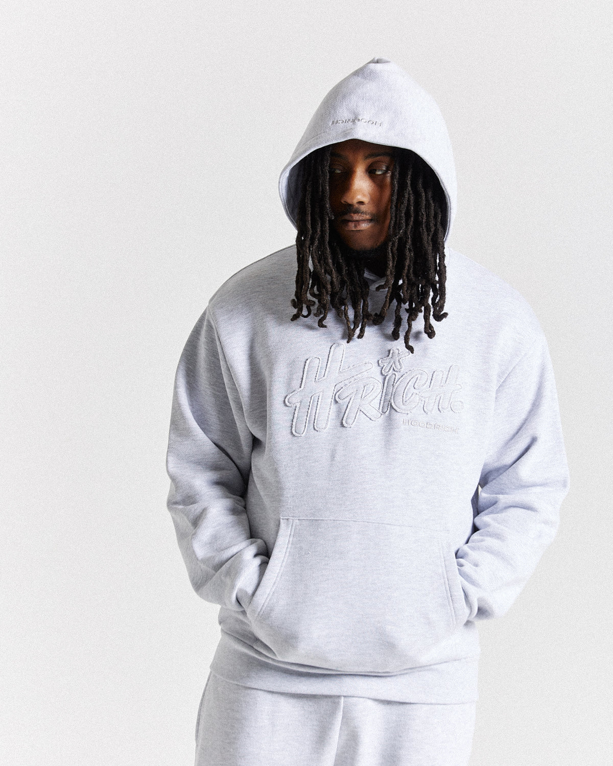 Displays a model wearing the light grey 'Hoodrich' branded men's Asthrich Full Tracksuit 