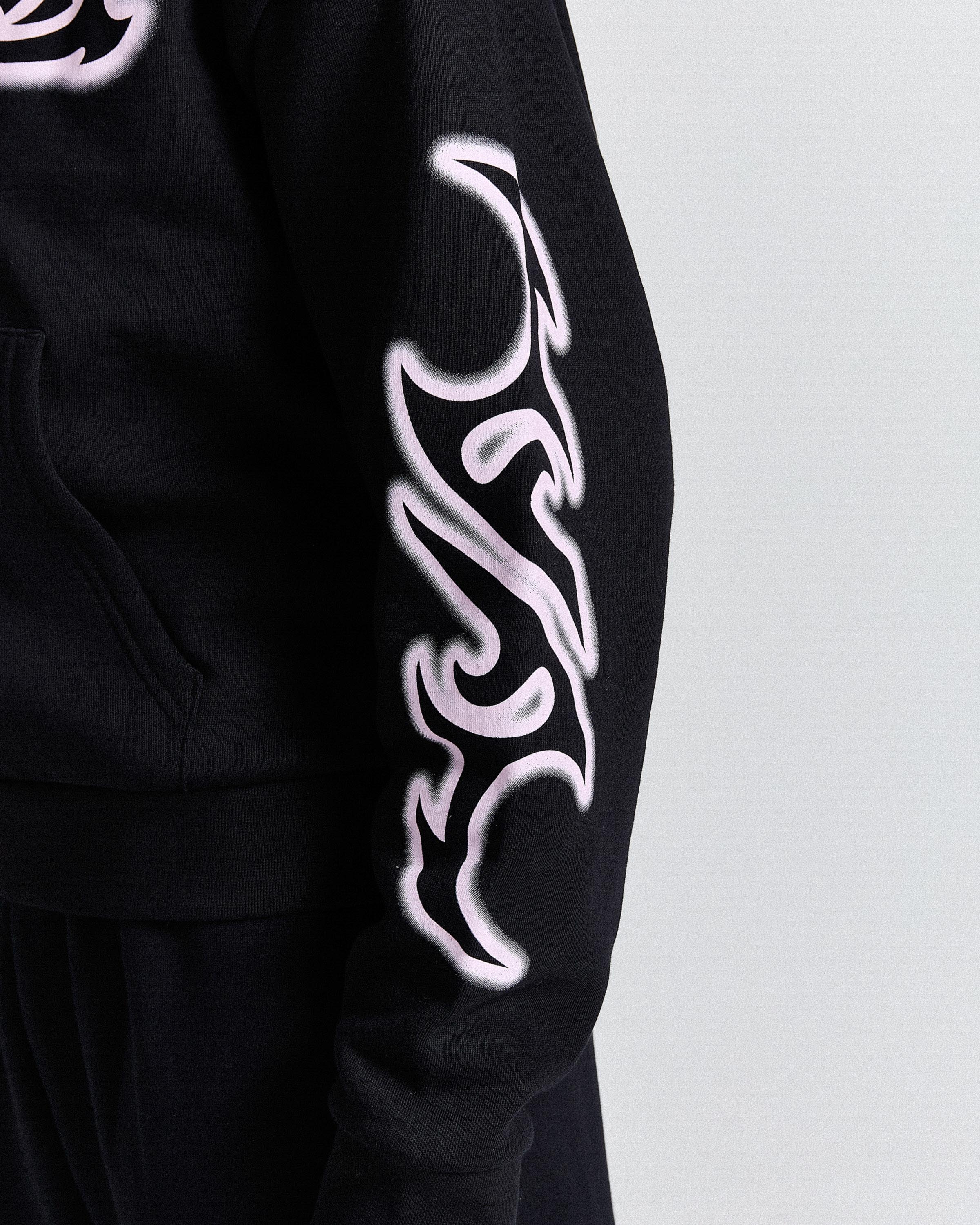 Black hoodie with white tribal designs on sleeves against a light gray background