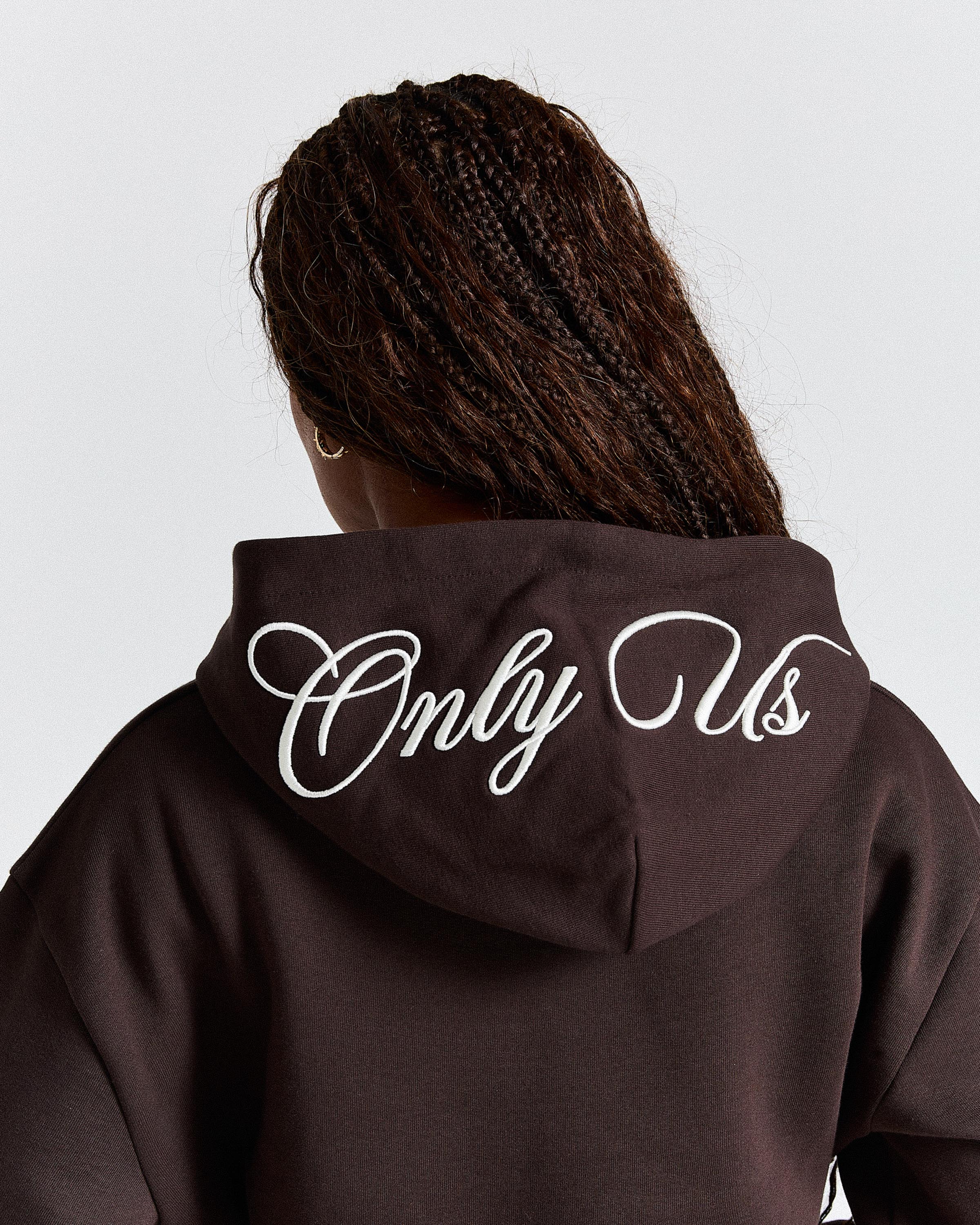 Person wearing a hoodie with 'Only Us' text on the back against a light gray background