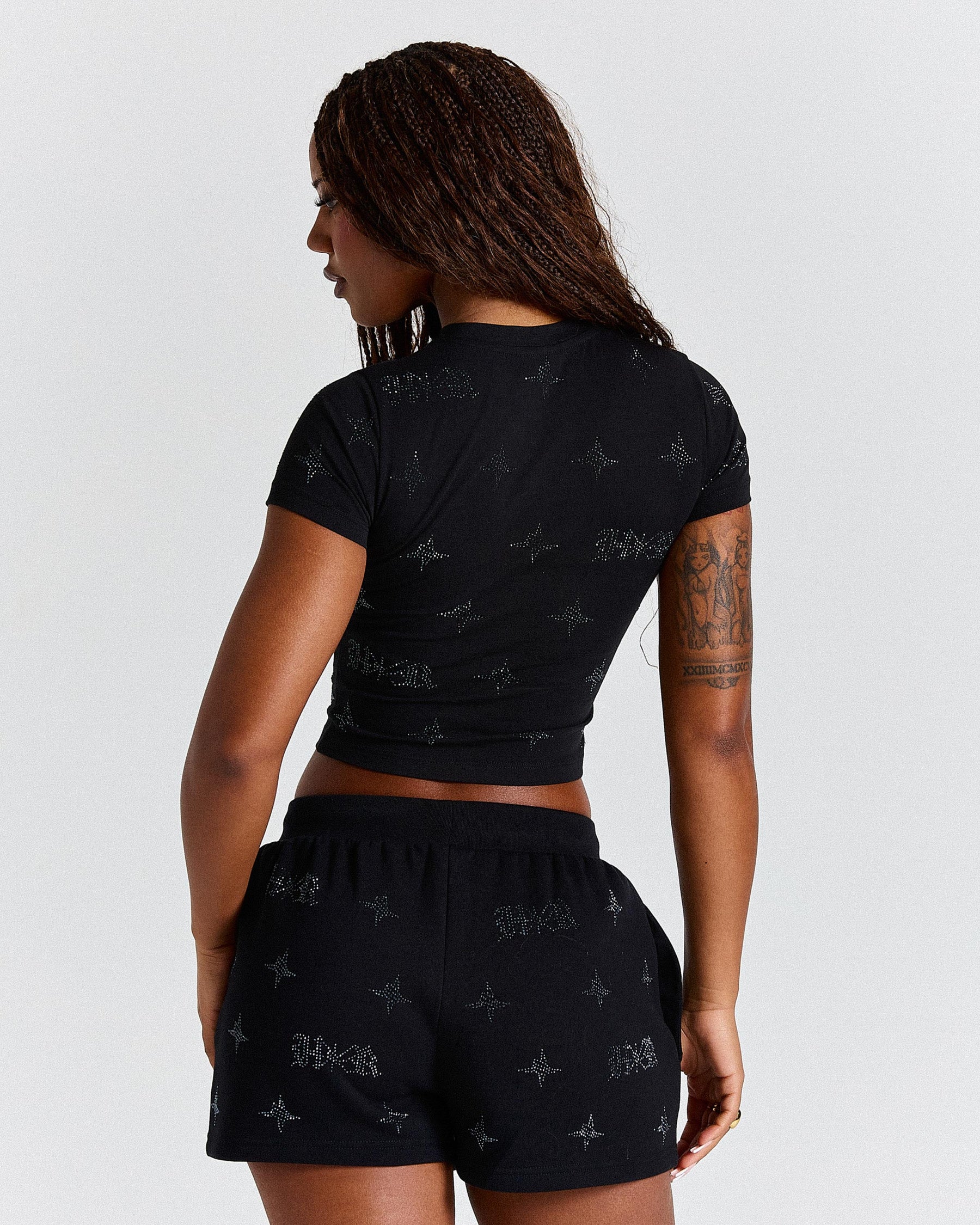 Person wearing a black patterned outfit on a plain background