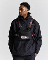 Person wearing a black jacket and bag with 'HOODRICH' branding, on a white background.