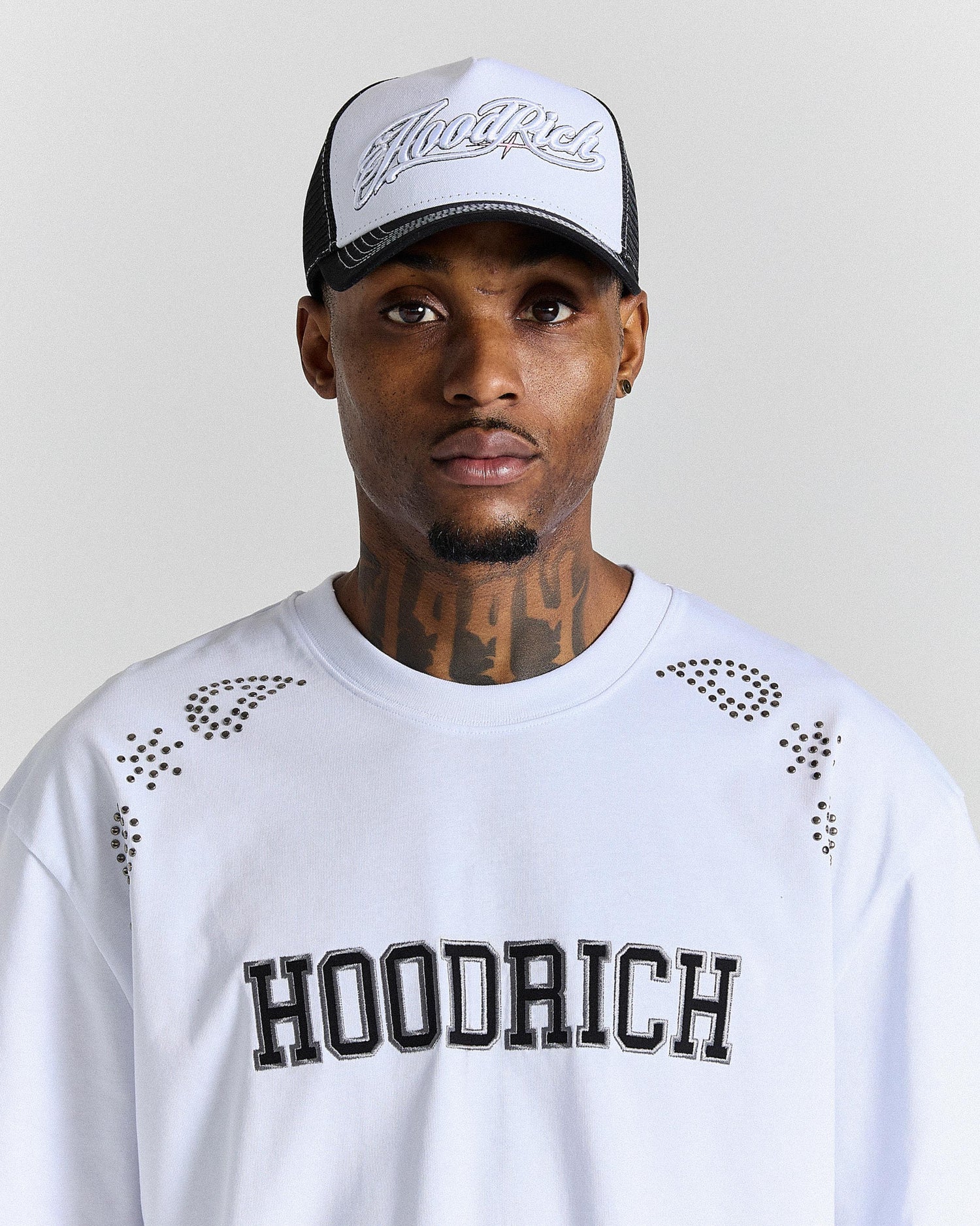 Person wearing a white 'Hoodrich' sweatshirt and cap with black text on a plain background