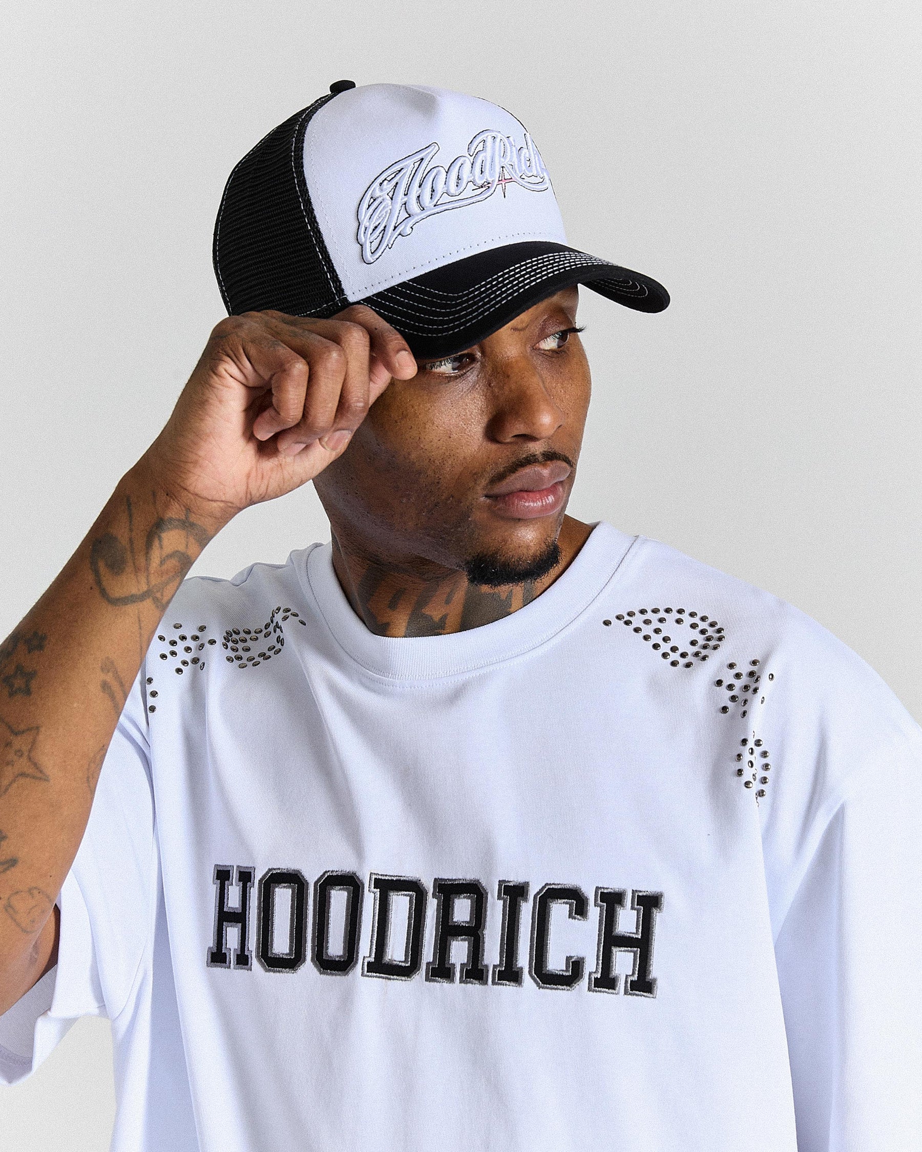 Person wearing a white cap and shirt with 'Hoodrich' branding on a light gray background